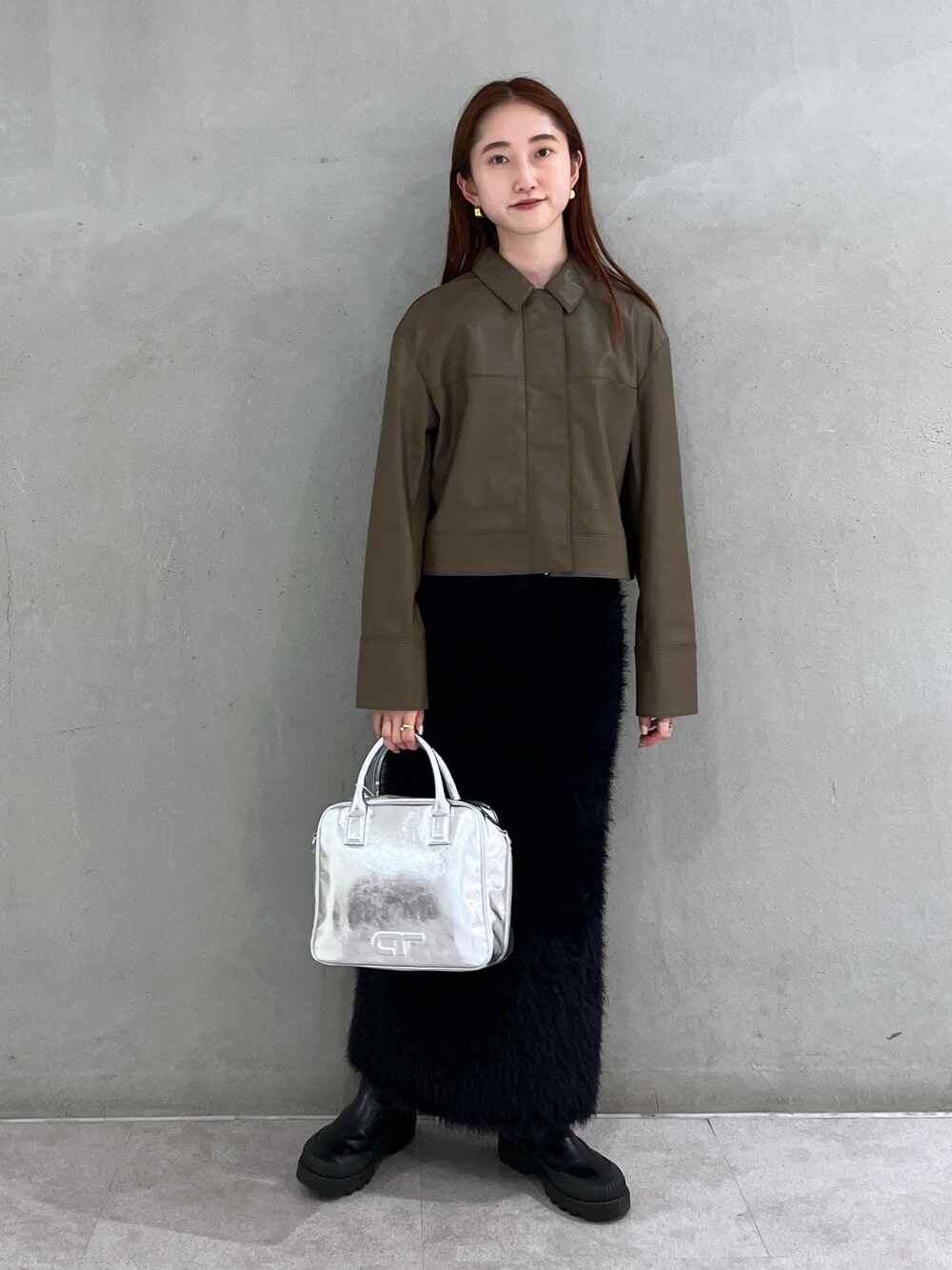 ブラウン系のブルゾン、シルバー系のボストンバッグ、ブラック系のスカートを着用したレディースの夏コーディネートの1枚目の写真