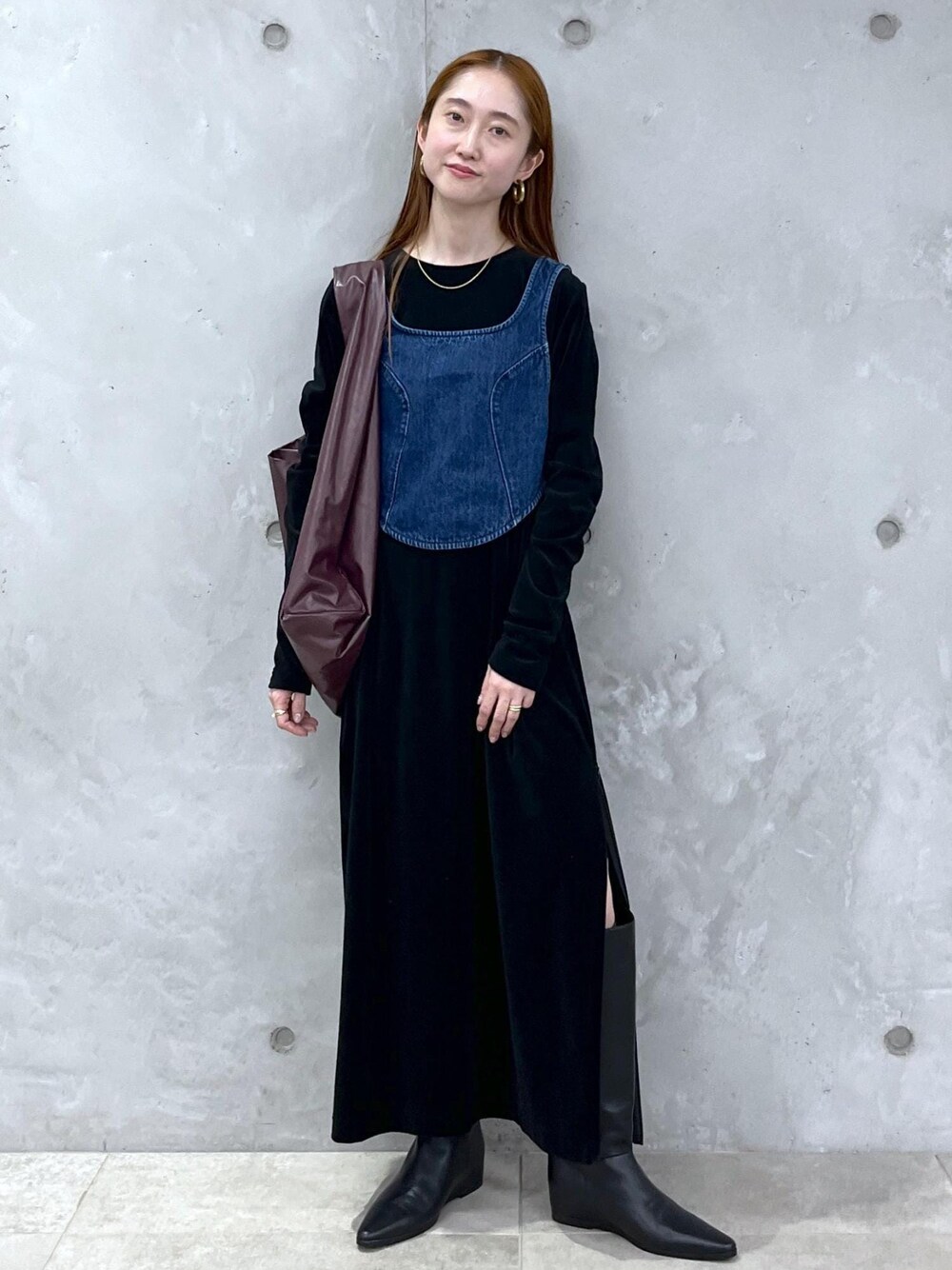 ブラック系のブーツ、ブラック系のワンピース、ブルー系のベストを着用したレディースの秋コーディネートの1枚目の写真