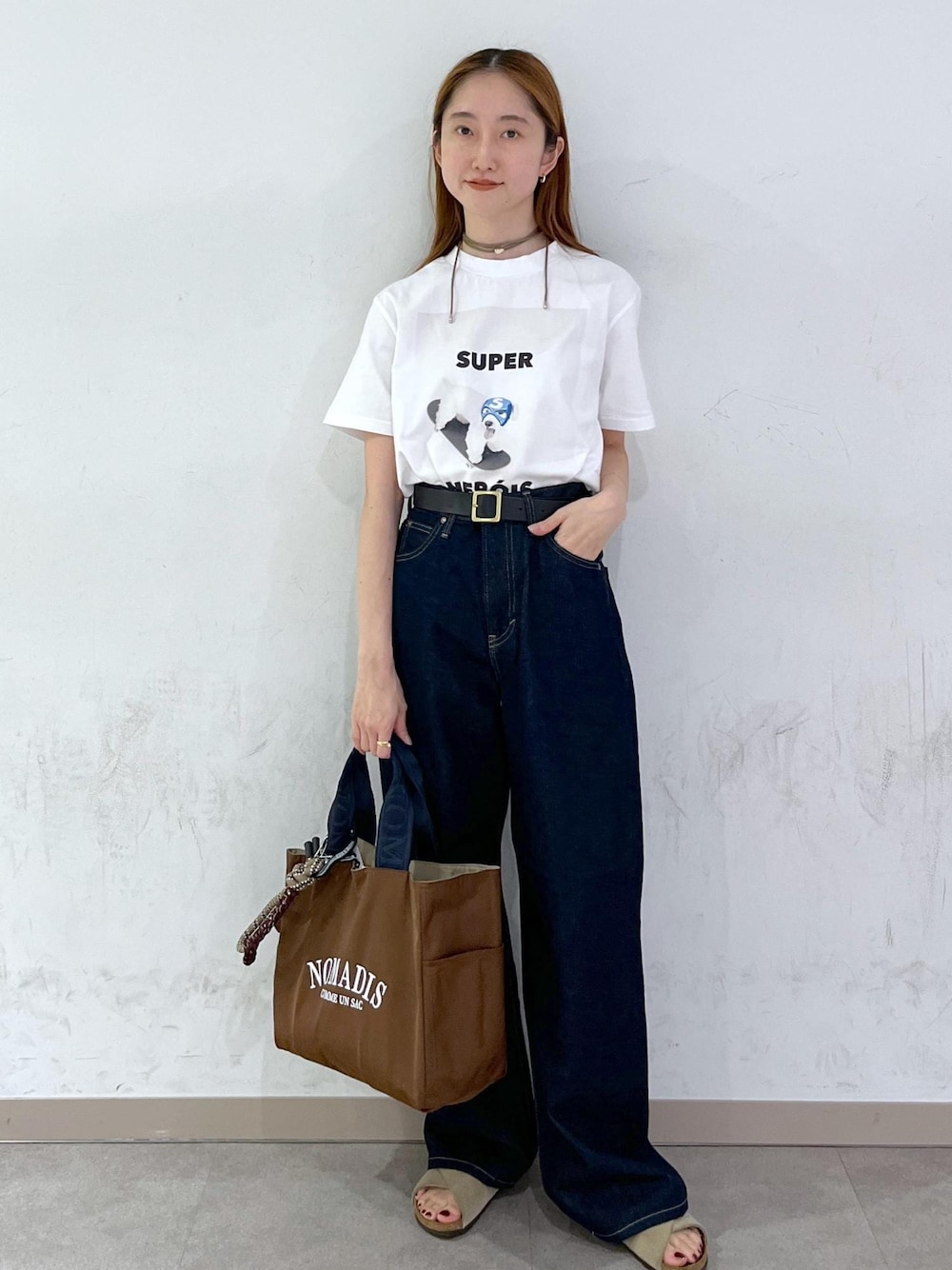 ブラウン系のトートバッグ、ブルー系のデニムパンツ、シルバー系のネックレスを着用したレディースの夏コーディネートの1枚目の写真