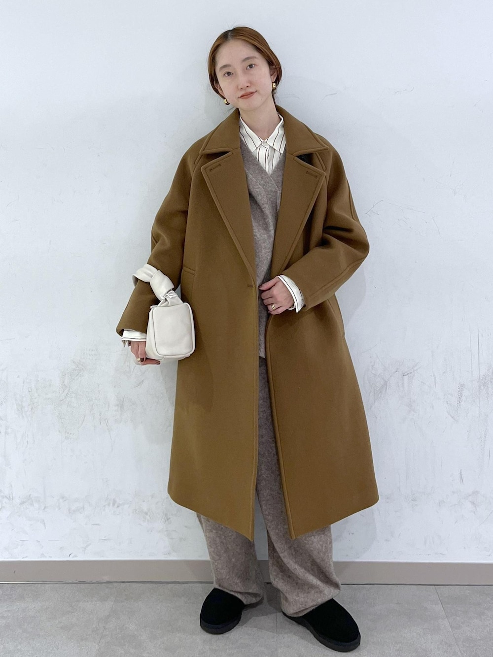 ホワイト系のハンドバッグ、イエロー系のステンカラーコート、ベージュ系のニット/セーターを着用したレディースの秋コーディネートの1枚目の写真