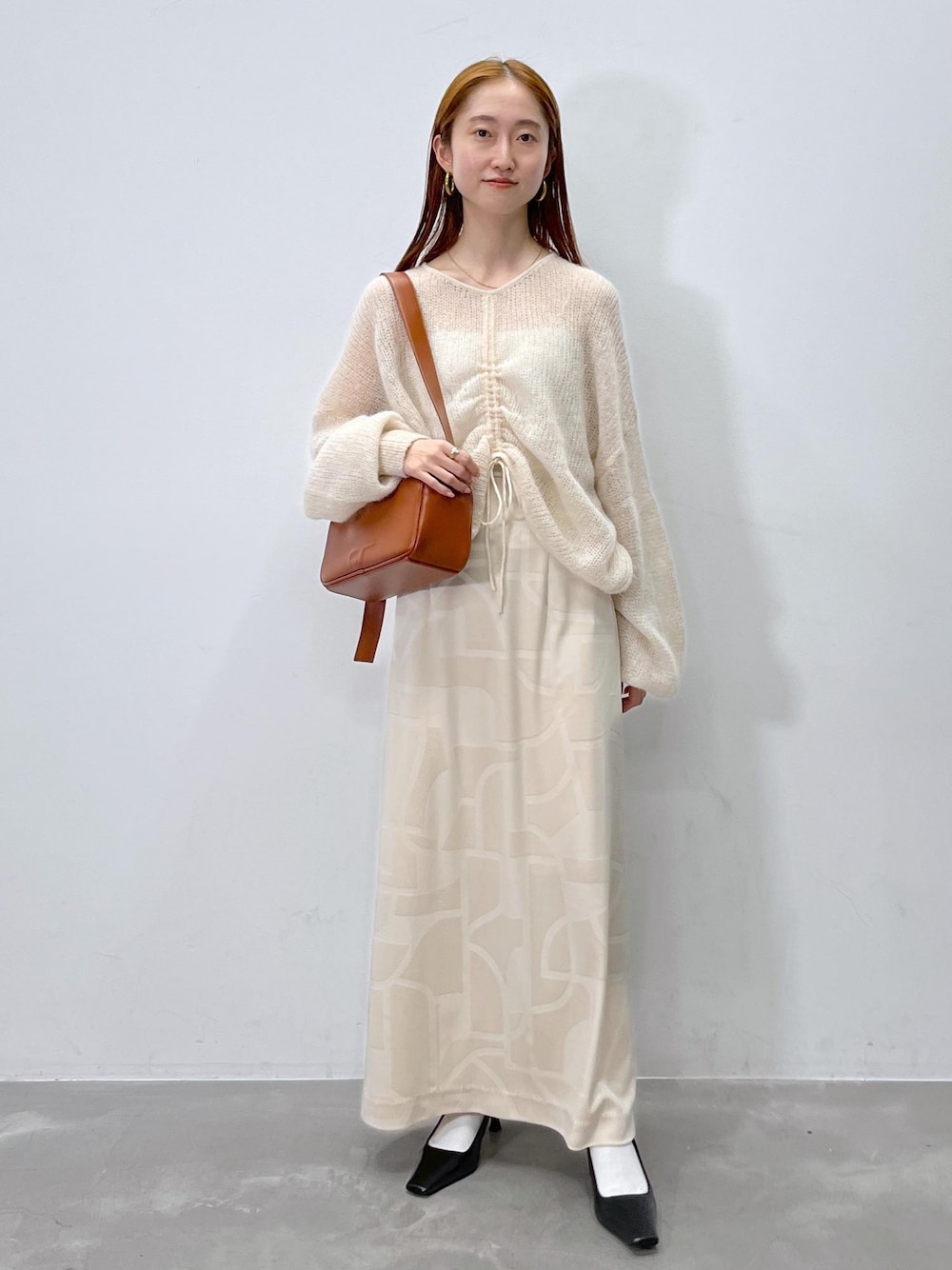 ホワイト系のスカート、ベージュ系のニット/セーター、ブラウン系のショルダーバッグを着用したレディースの夏コーディネートの1枚目の写真