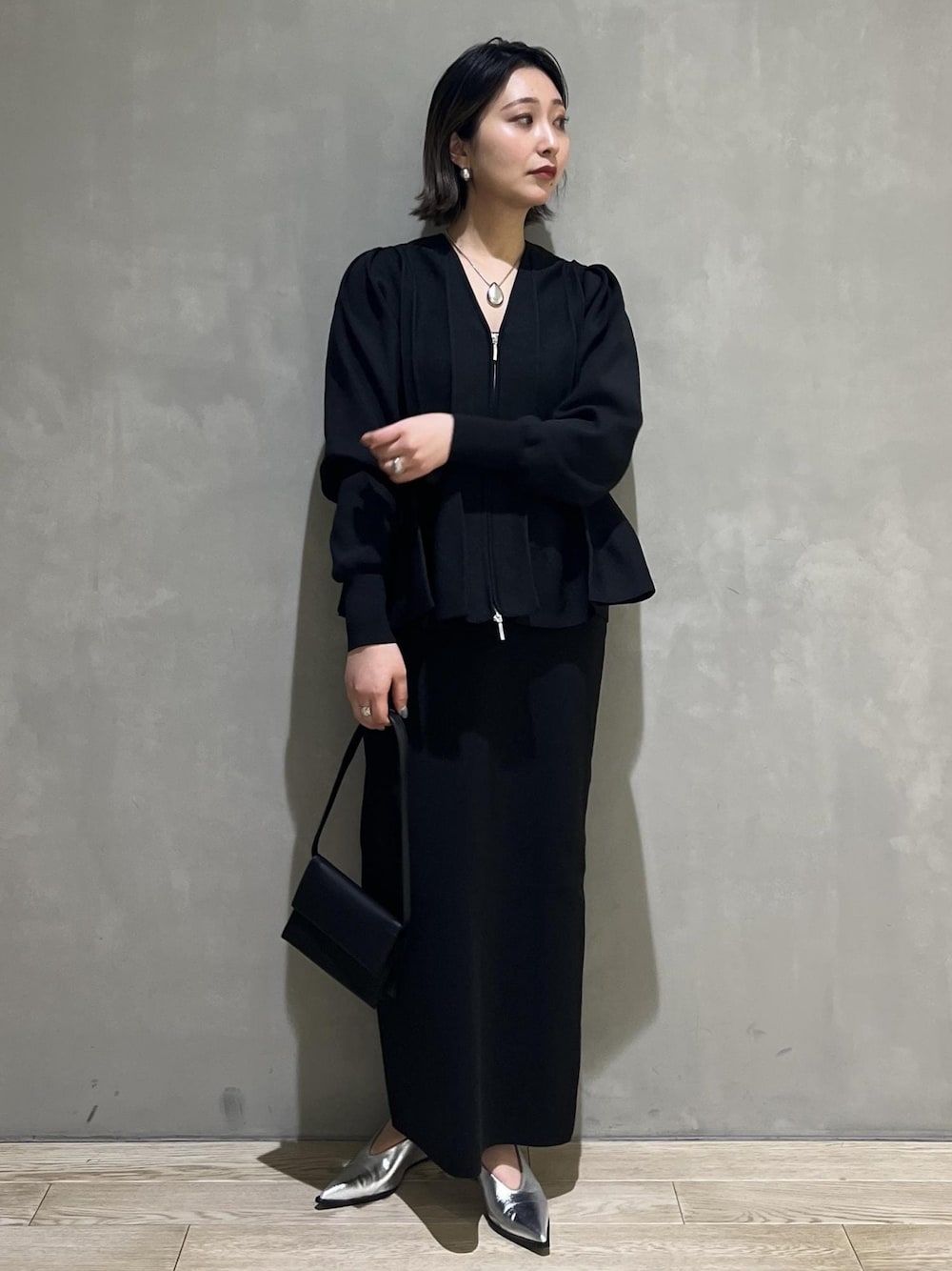 シルバー系のパンプス、ブラック系のカーディガン/ボレロ、ブラック系のワンピースを着用したレディースの春コーディネートの1枚目の写真