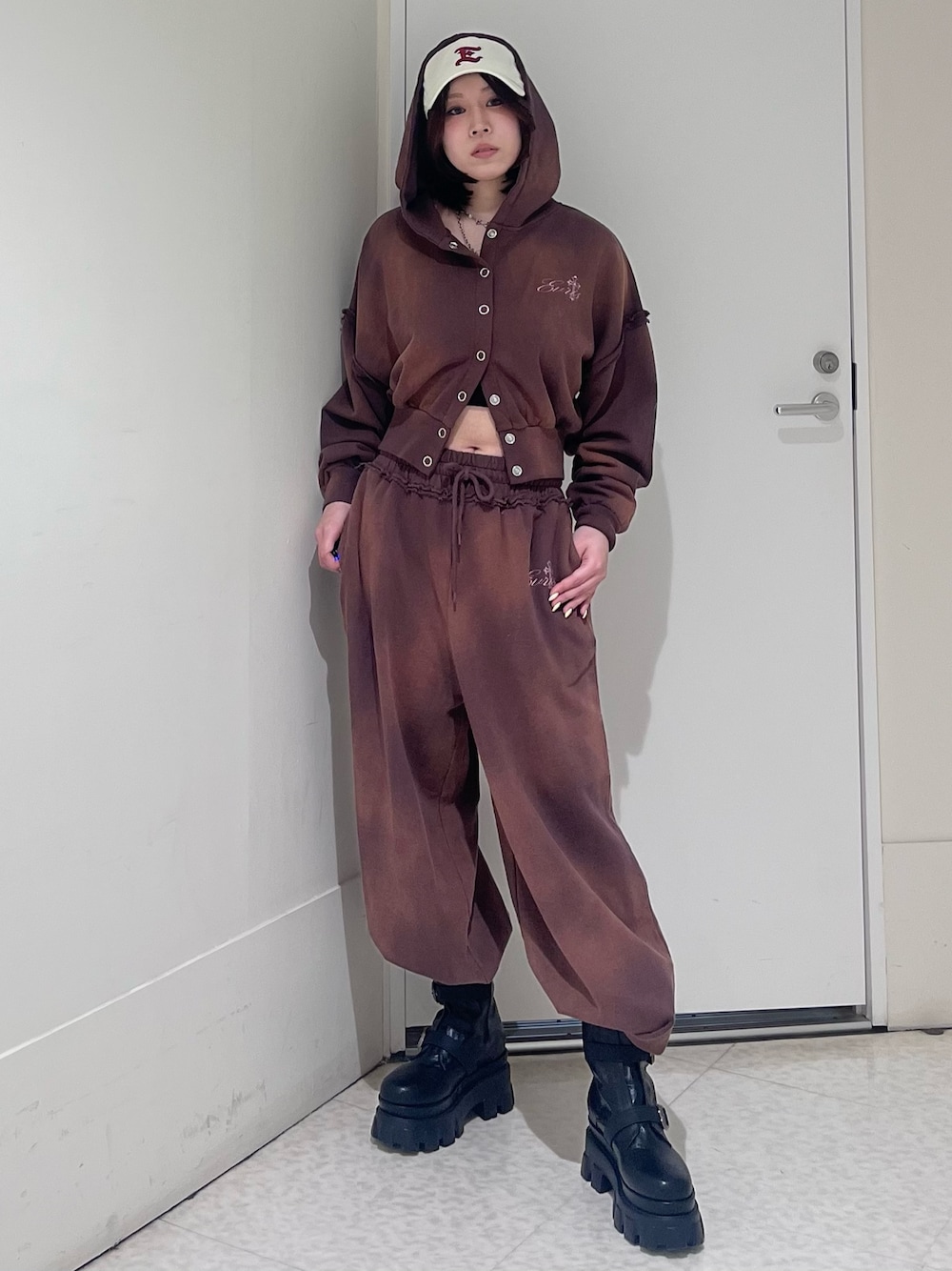 ブラウン系のパーカー、ブラウン系のスウェットパンツ、ブラック系のブーツを着用したレディースの春コーディネートの1枚目の写真