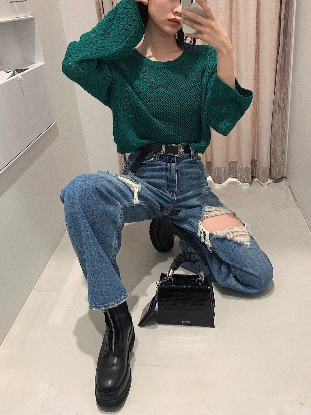 ブラック系のブーツ、ブルー系のデニムパンツ、グリーン系のニット/セーターを着用したレディースの春コーディネートの1枚目の写真