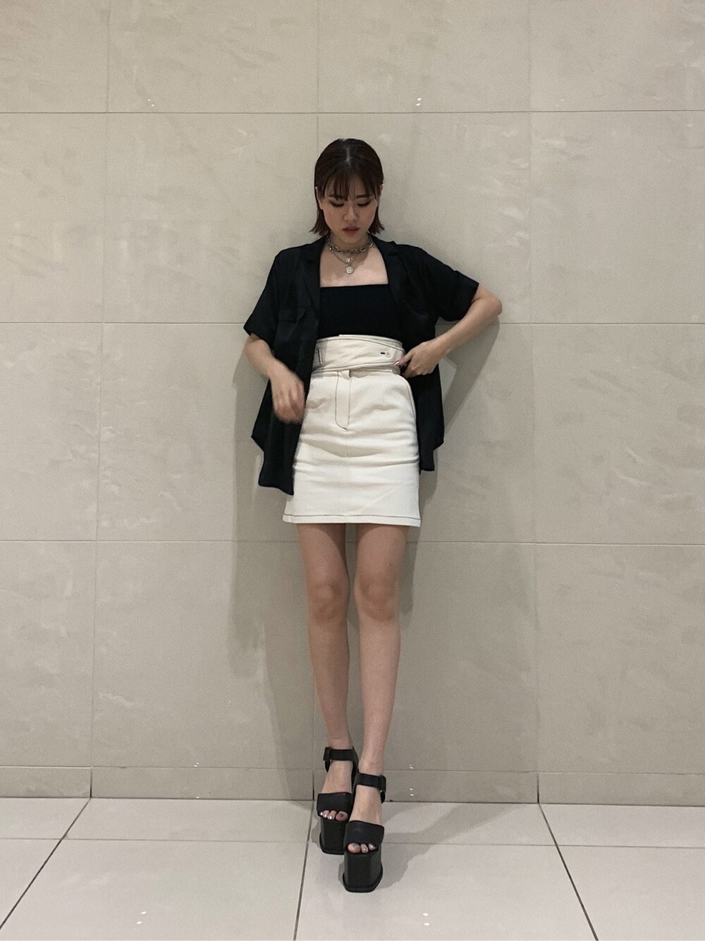 ホワイト系のスカート、ブラック系のサンダル、ブラック系のシャツ/ブラウスを着用したレディースの春コーディネートの1枚目の写真