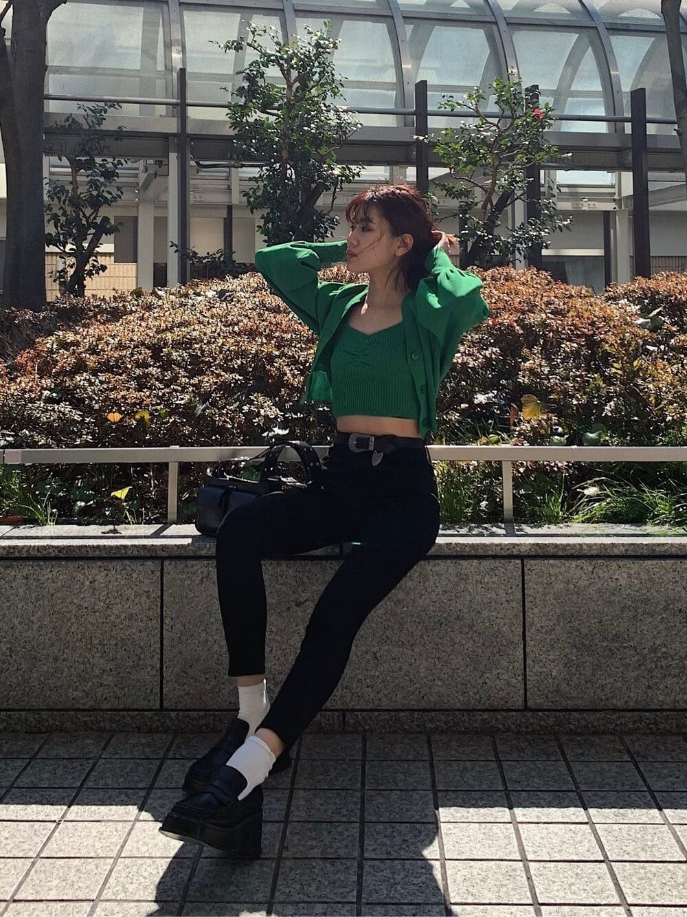 ブラック系のデニムパンツ、ブラック系のローファー、ブラック系のショルダーバッグを着用したレディースの春コーディネートの1枚目の写真