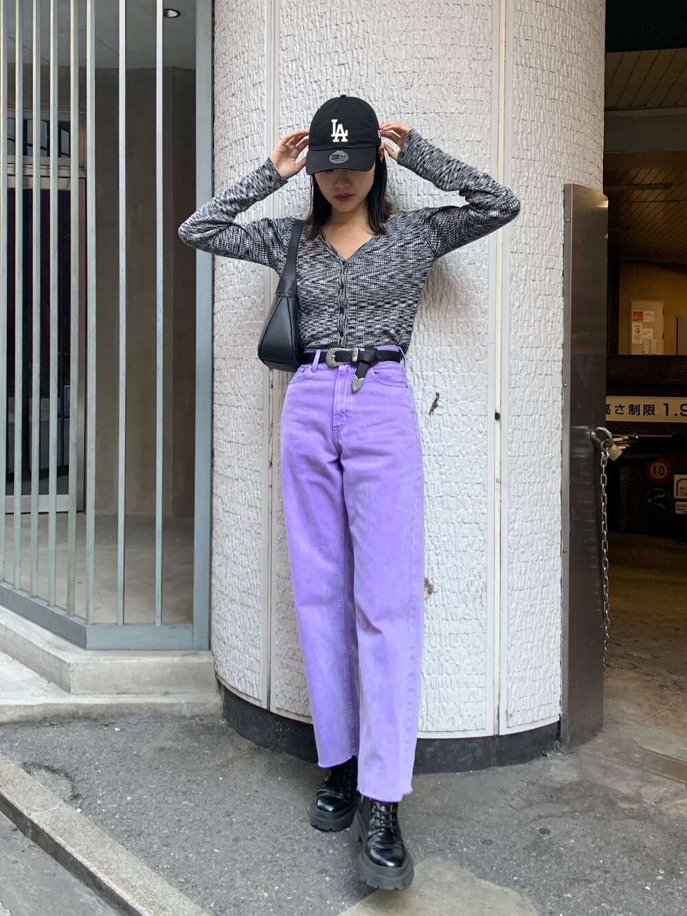 パープル系のデニムパンツ、ブラック系のニット/セーター、ブラック系のハンドバッグを着用したレディースの冬コーディネートの1枚目の写真