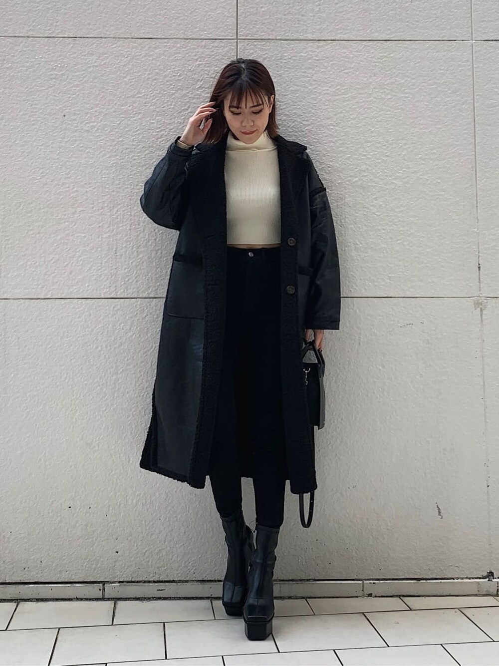 ブラック系のデニムパンツ、ブラック系のショルダーバッグ、ブラック系のブーツを着用したレディースの冬コーディネートの1枚目の写真