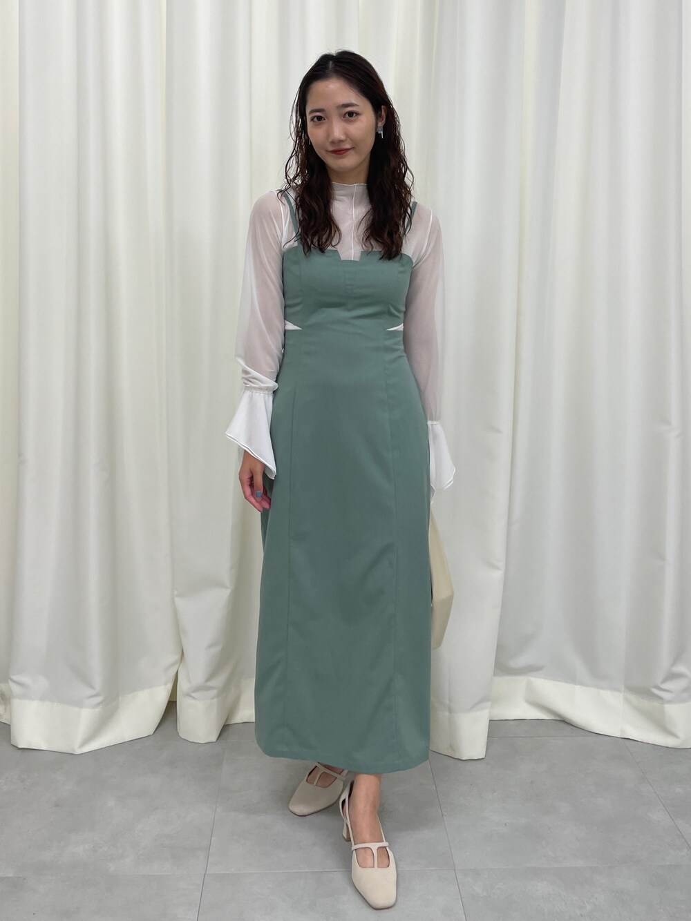 グリーン系のワンピース、ホワイト系のパンプスを着用したレディースの春コーディネートの1枚目の写真