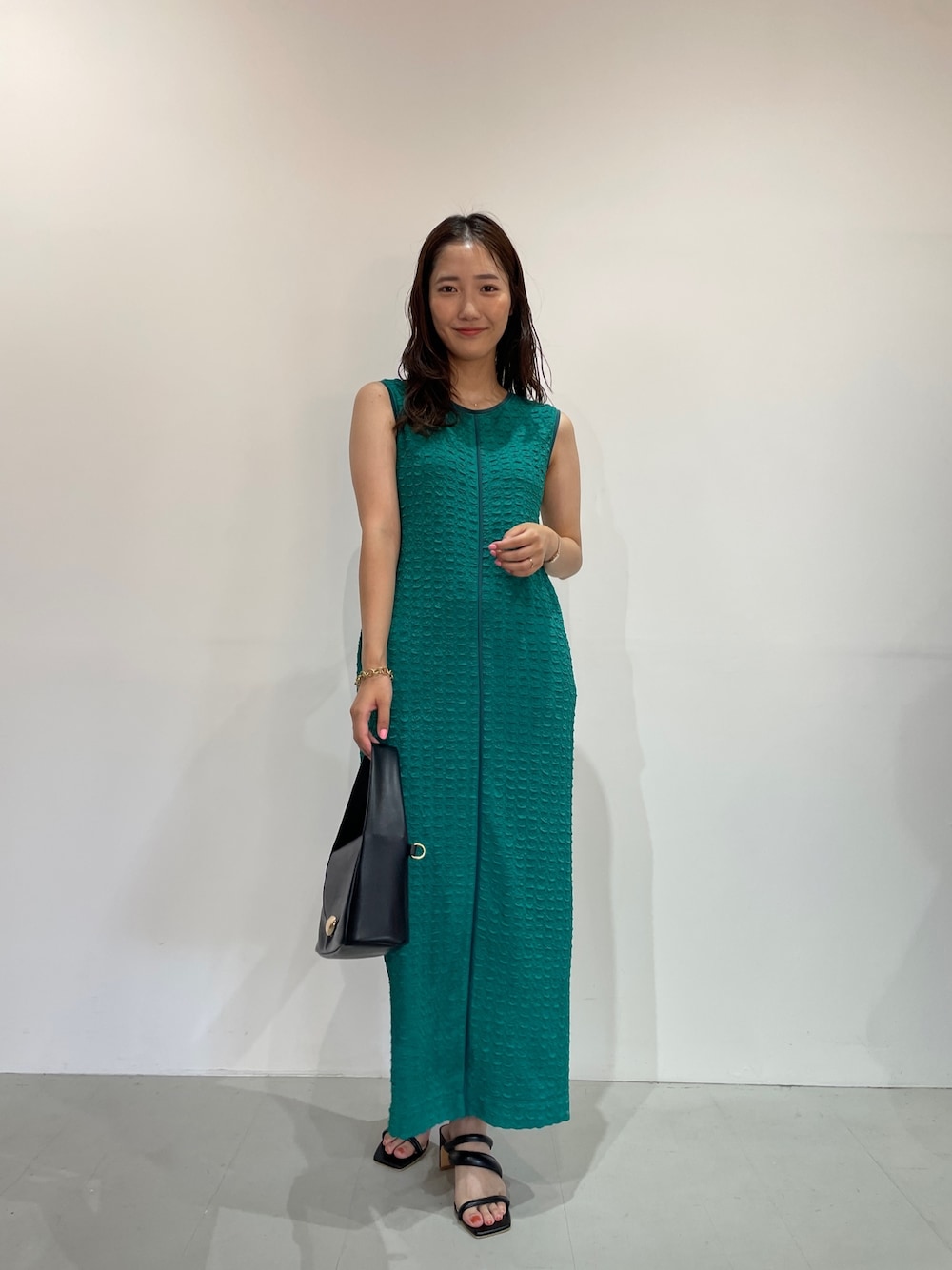 グリーン系のワンピース、ブラック系のサンダル、ブラック系のハンドバッグを着用したレディースの夏コーディネートの1枚目の写真