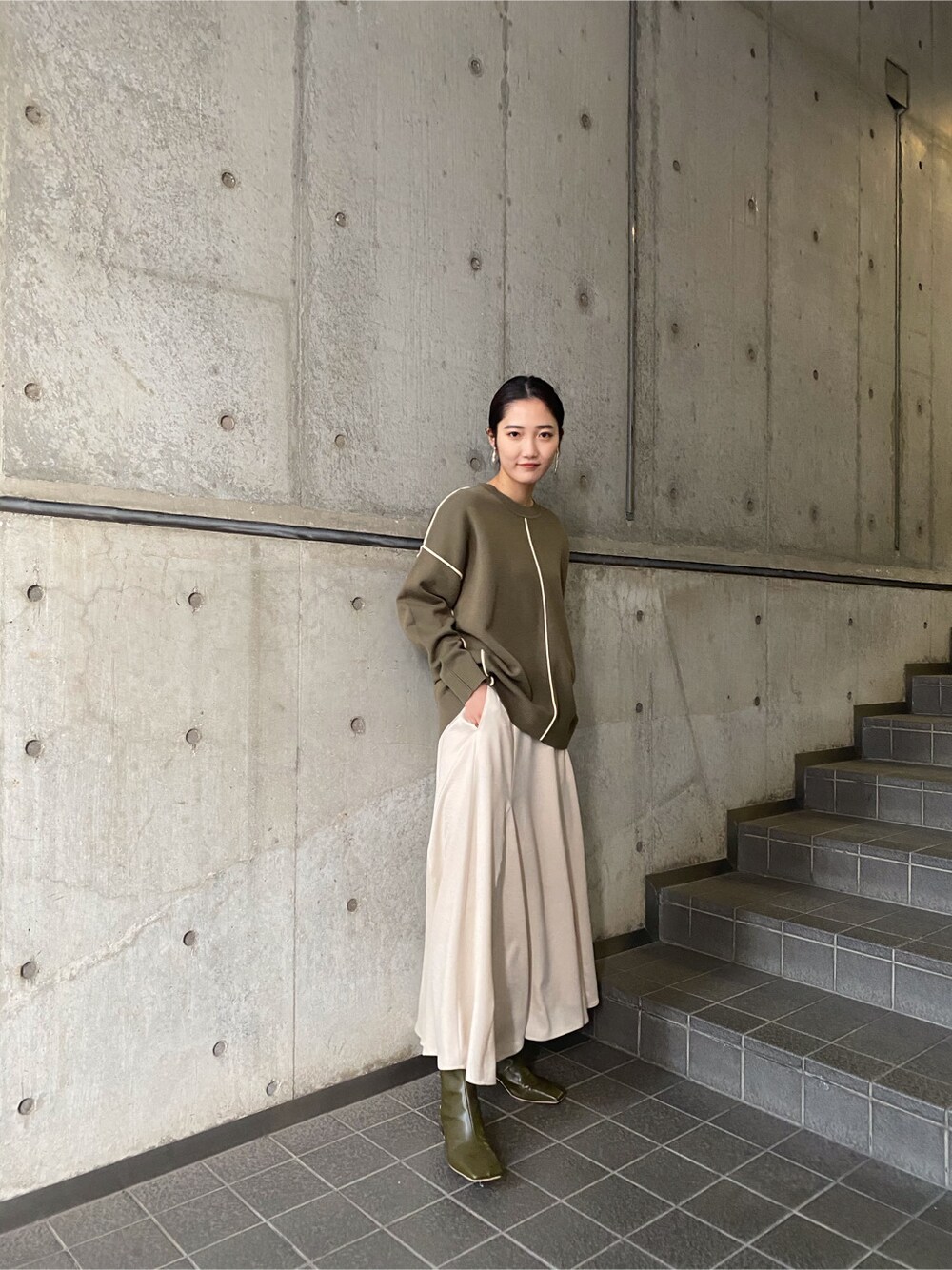 ホワイト系のスカート、ベージュ系のブーツ、ベージュ系のニット/セーターを着用したレディースの冬コーディネートの1枚目の写真