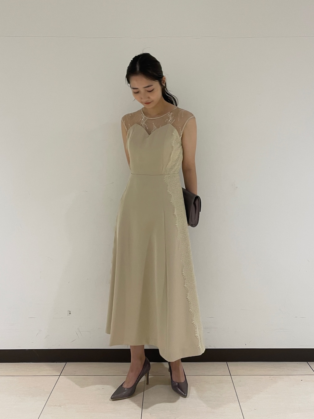 ベージュ系のドレス、シルバー系のパンプス、シルバー系のクラッチバッグを着用したレディースの春コーディネートの1枚目の写真