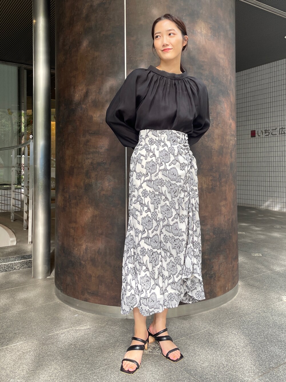 ベージュ系のサンダル、ブラック系のスカート、ブラック系のシャツ/ブラウスを着用したレディースの冬コーディネートの1枚目の写真