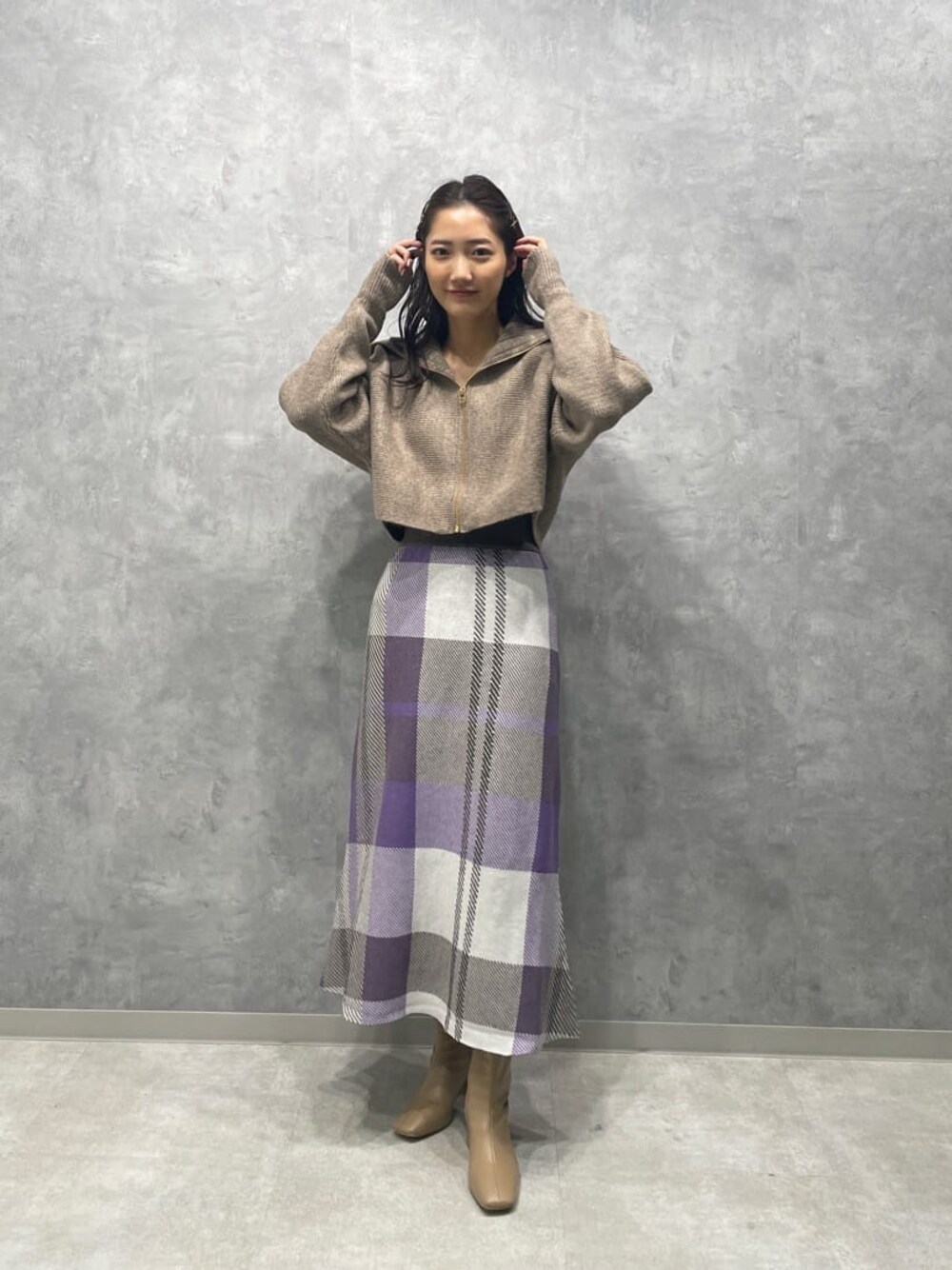 ベージュ系のブーツ、ベージュ系のカーディガン/ボレロ、パープル系のスカートを着用したレディースの秋コーディネートの1枚目の写真