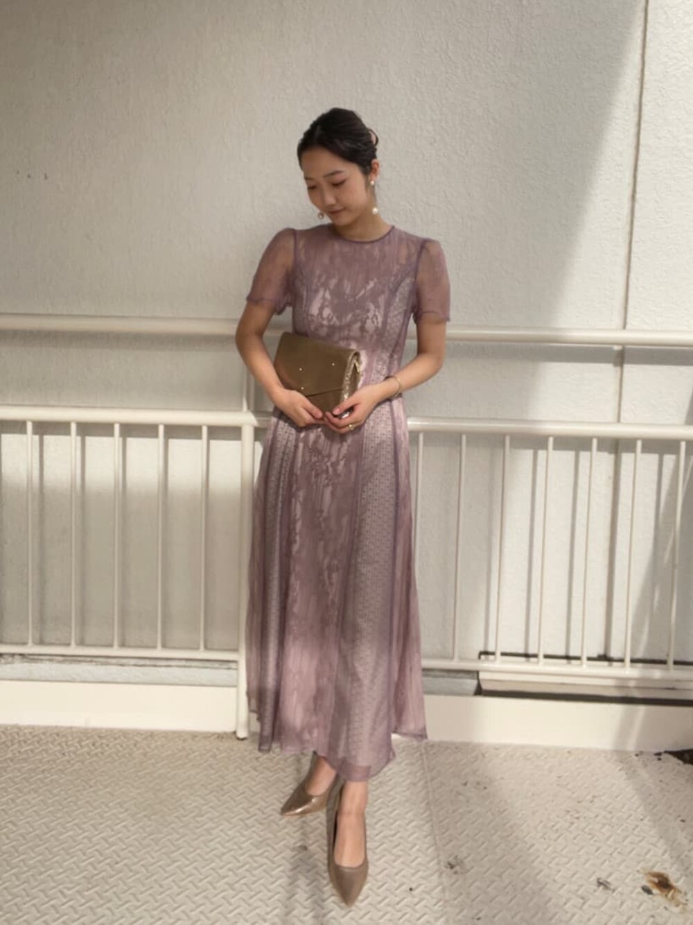 ゴールド系のパンプス、ゴールド系のクラッチバッグ、パープル系のドレスを着用したレディースの冬コーディネートの1枚目の写真