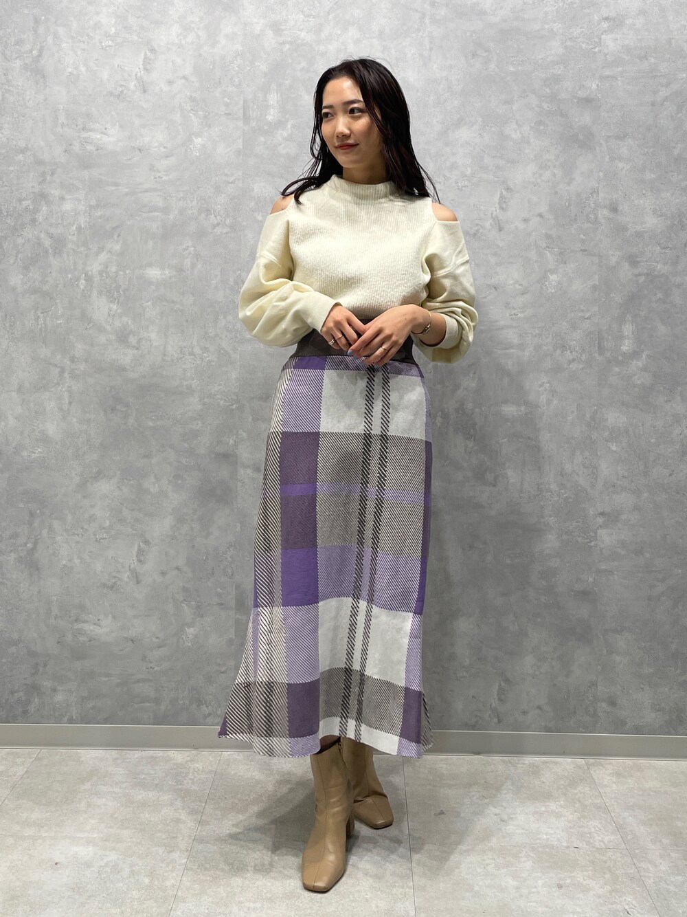 ベージュ系のブーツ、ホワイト系のニット/セーター、パープル系のスカートを着用したレディースの冬コーディネートの1枚目の写真