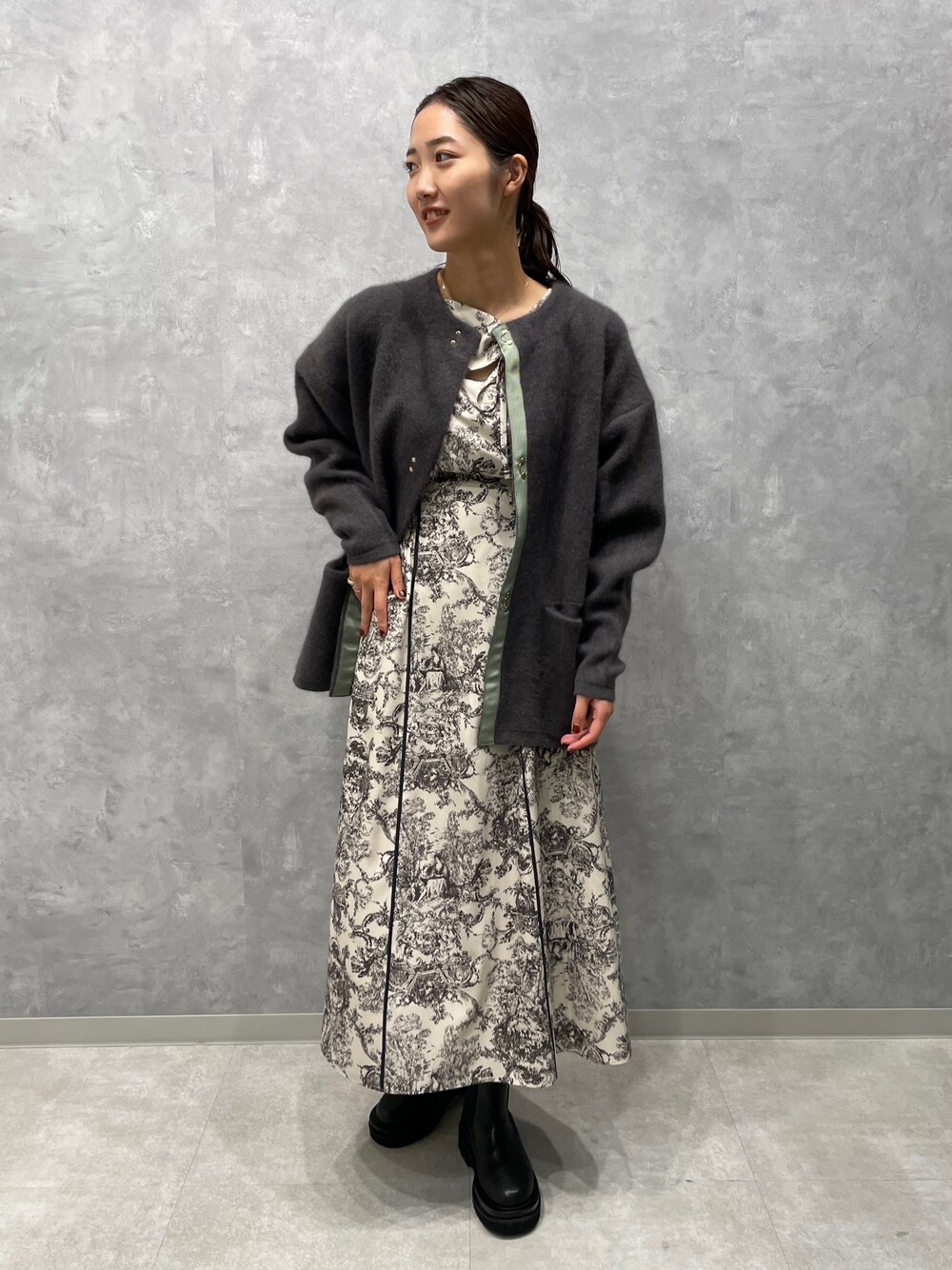 グレー系のカーディガン/ボレロ、ホワイト系のワンピース、ブラック系のブーツを着用したレディースの冬コーディネートの1枚目の写真