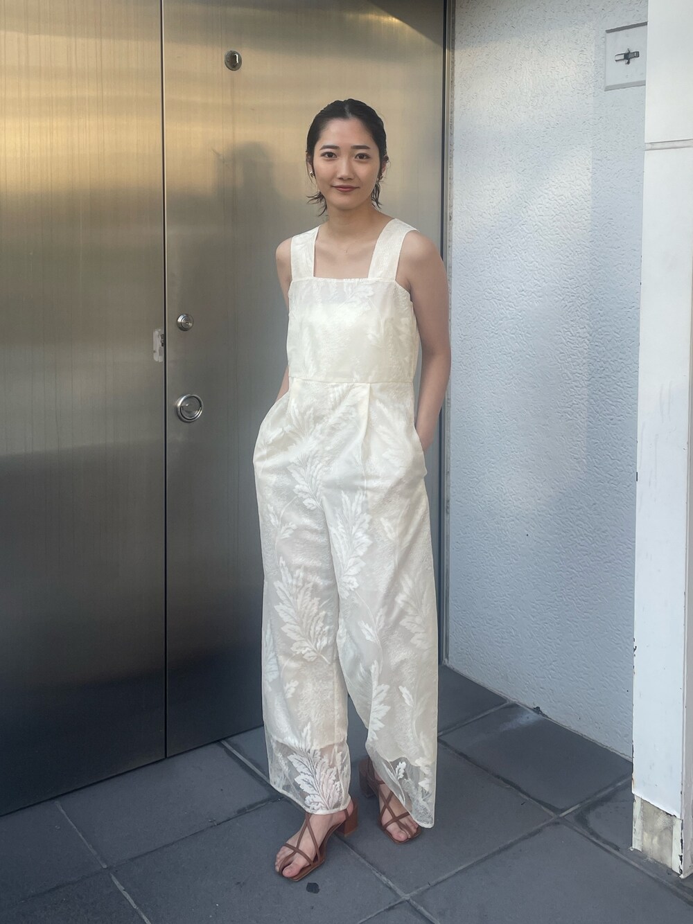 ブラウン系のサンダル、ホワイト系のつなぎ/オールインワン、ベージュ系の折りたたみ傘を着用したレディースの冬コーディネートの1枚目の写真