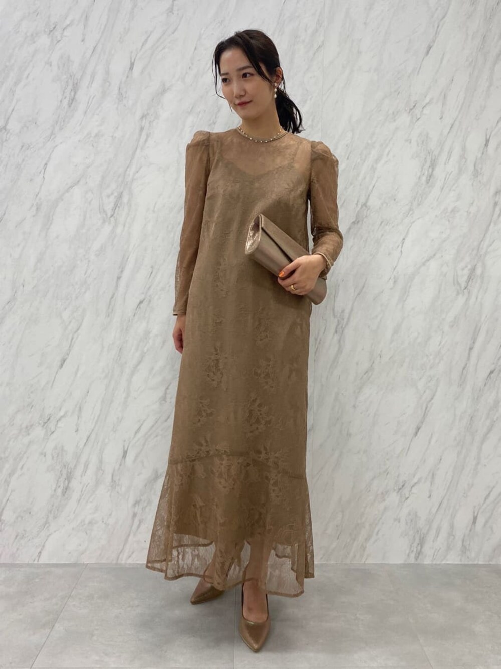 ゴールド系のパンプス、ゴールド系のクラッチバッグ、ベージュ系のドレスを着用したレディースの夏コーディネートの1枚目の写真