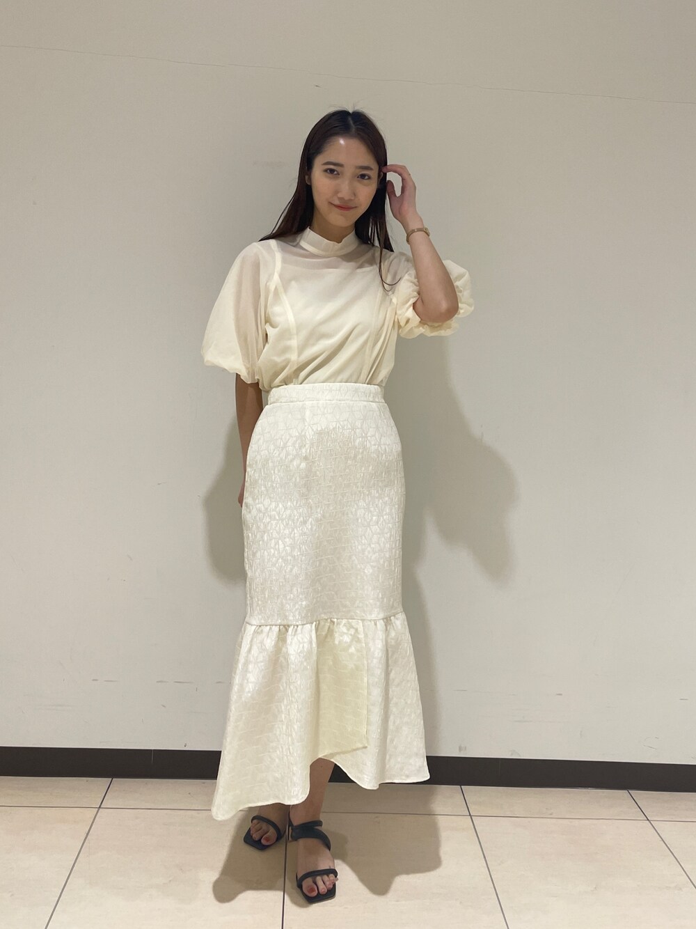 ホワイト系のシャツ/ブラウス、ホワイト系のスカート、ブラック系のサンダルを着用したレディースの春コーディネートの1枚目の写真