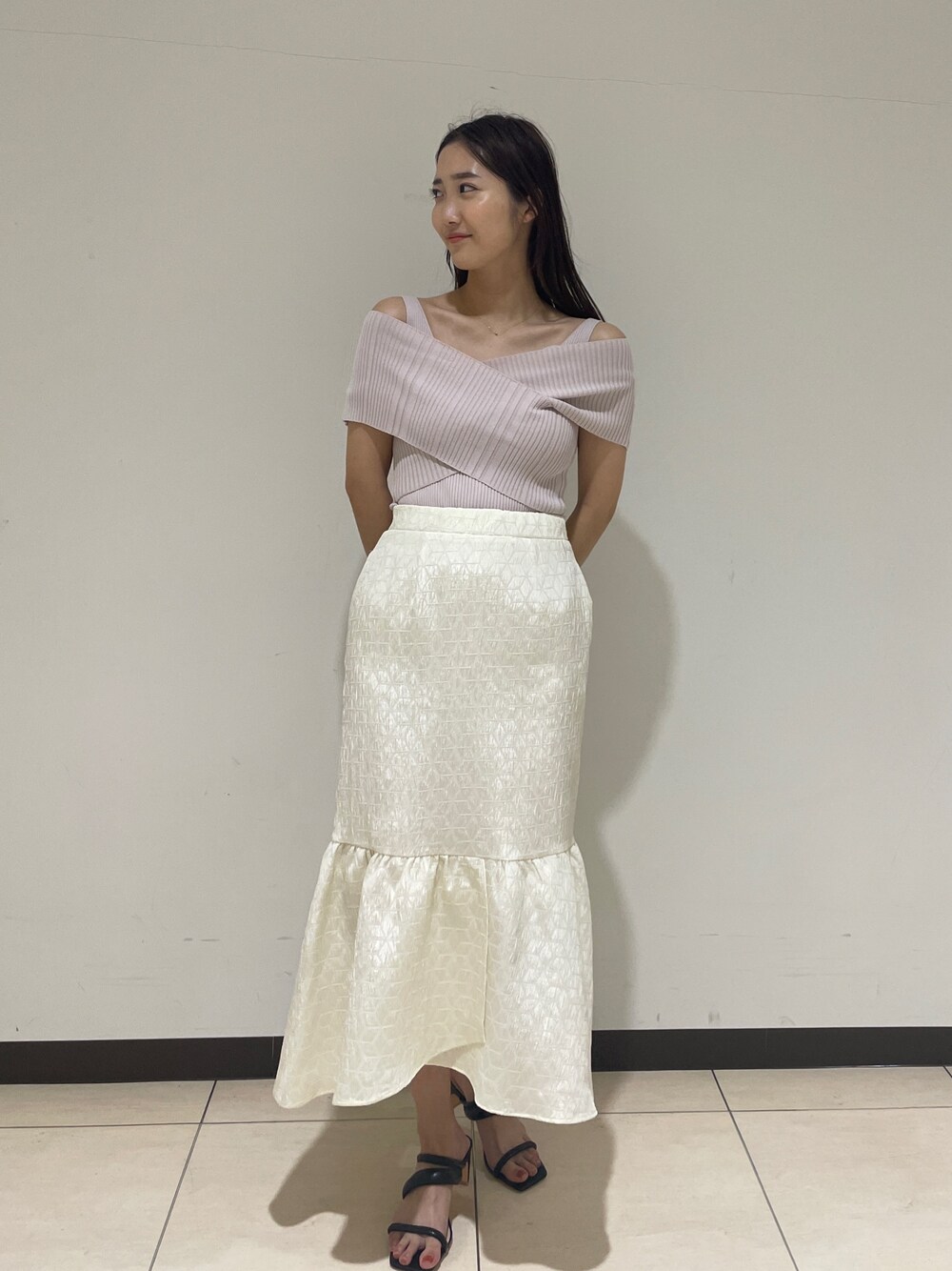 ホワイト系のスカート、ベージュ系のニット/セーター、ブラック系のサンダルを着用したレディースの春コーディネートの1枚目の写真