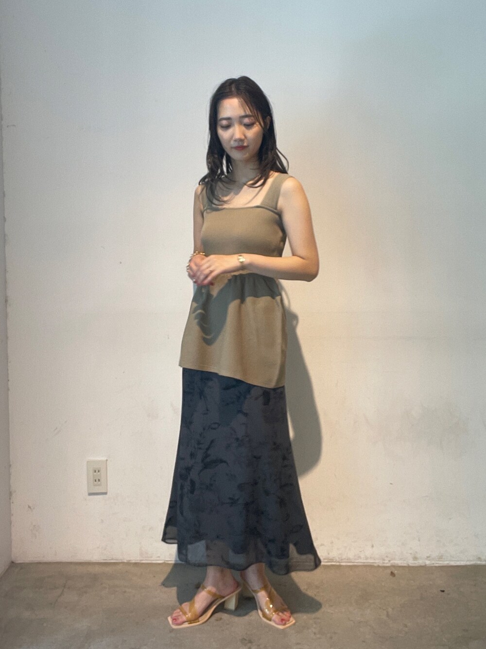 グレー系のスカート、イエロー系のサンダル、ベージュ系のニット/セーターを着用したレディースの夏コーディネートの1枚目の写真