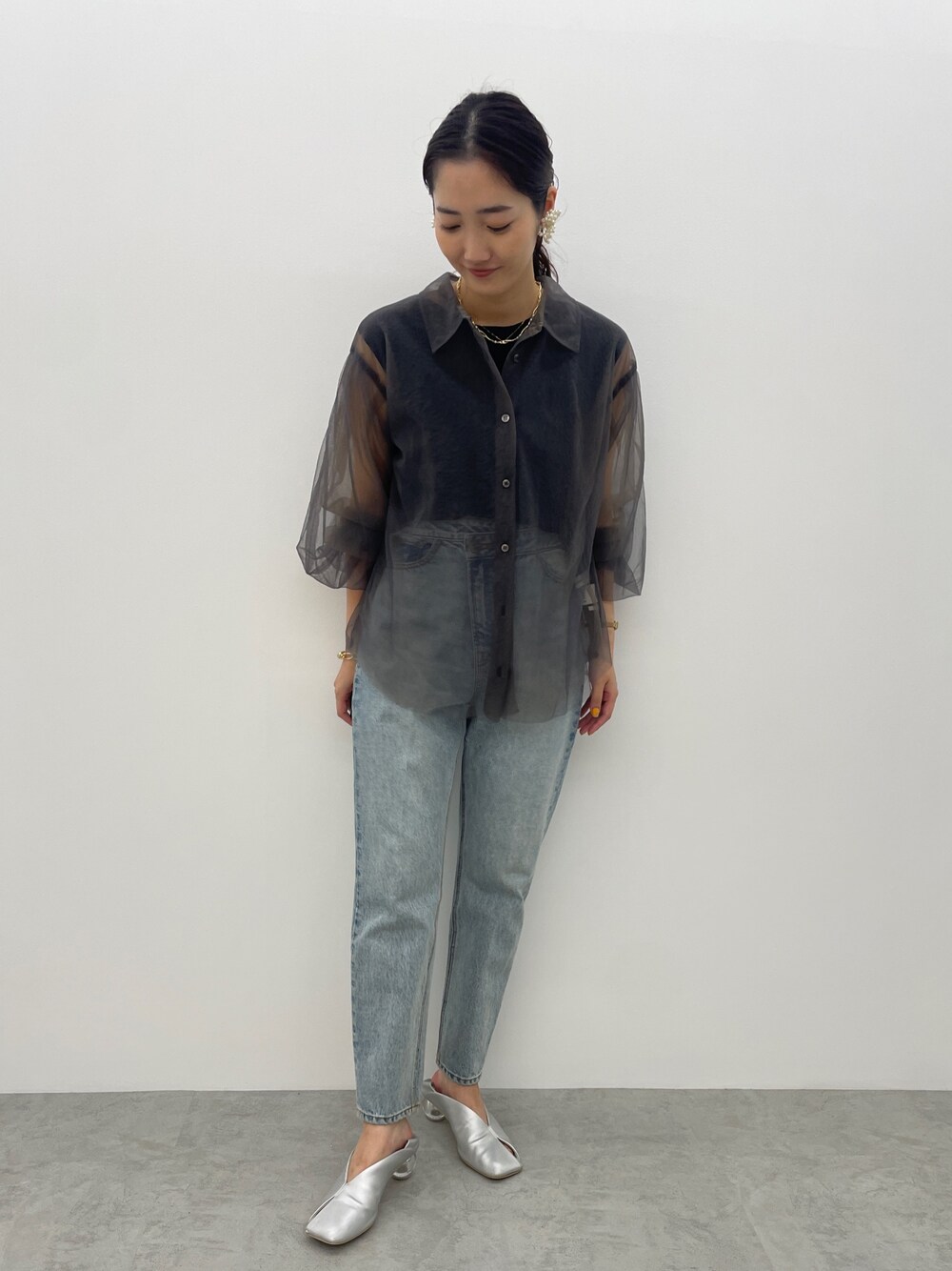 ブルー系のデニムパンツ、シルバー系のパンプス、ブラック系のニット/セーターを着用したレディースの夏コーディネートの1枚目の写真