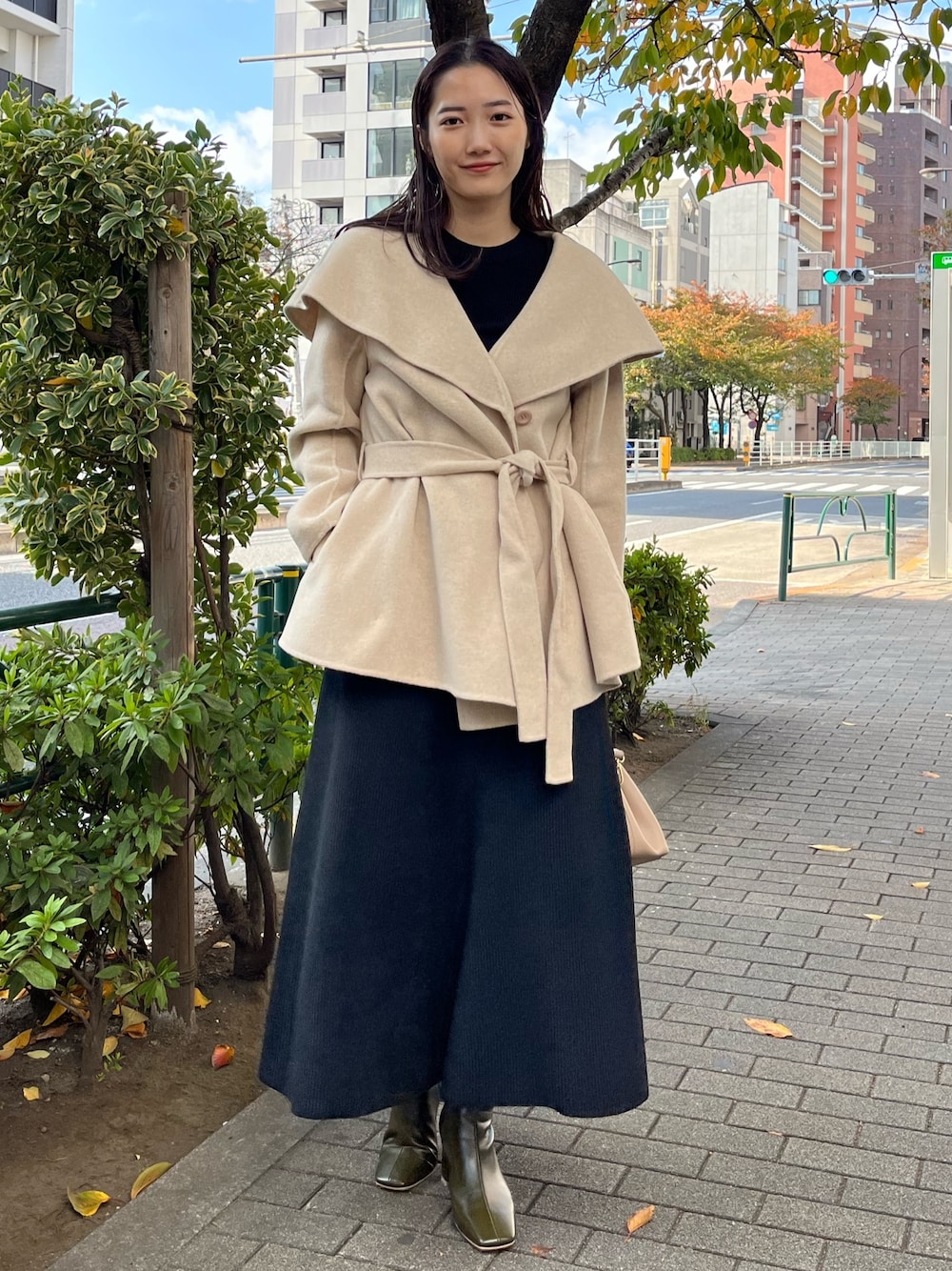 ブラック系のスカート、ブラック系のニット/セーター、グリーン系のブーツを着用したレディースの秋コーディネートの1枚目の写真