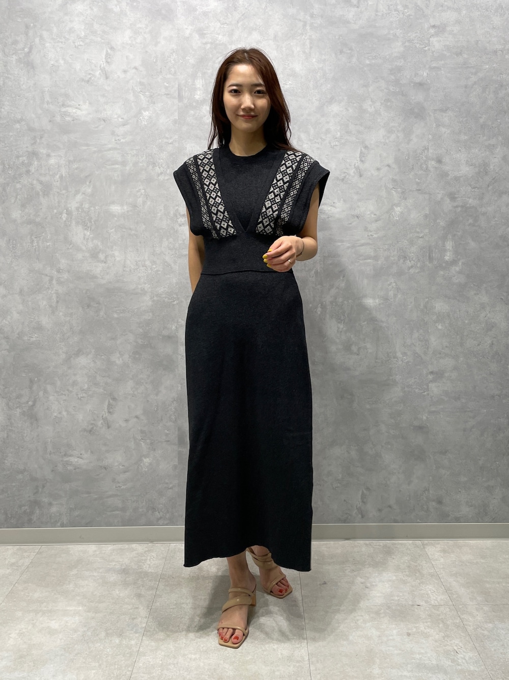 ベージュ系のサンダル、ブラック系のワンピースを着用したレディースの春コーディネートの1枚目の写真