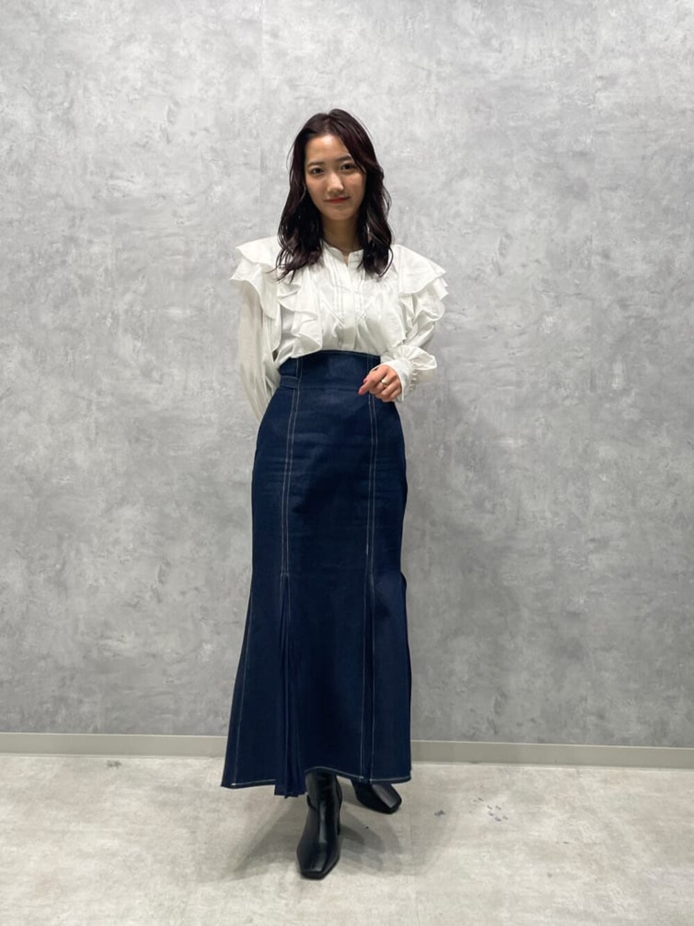 ブラック系のブーツ、ブルー系のスカート、ホワイト系のシャツ/ブラウスを着用したレディースの秋コーディネートの1枚目の写真