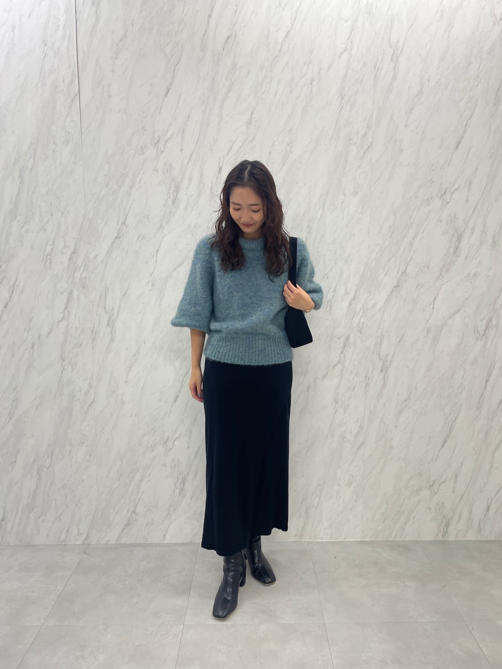 グリーン系のニット/セーター、ブラック系のブーツ、ブラック系のスカートを着用したレディースの冬コーディネートの1枚目の写真