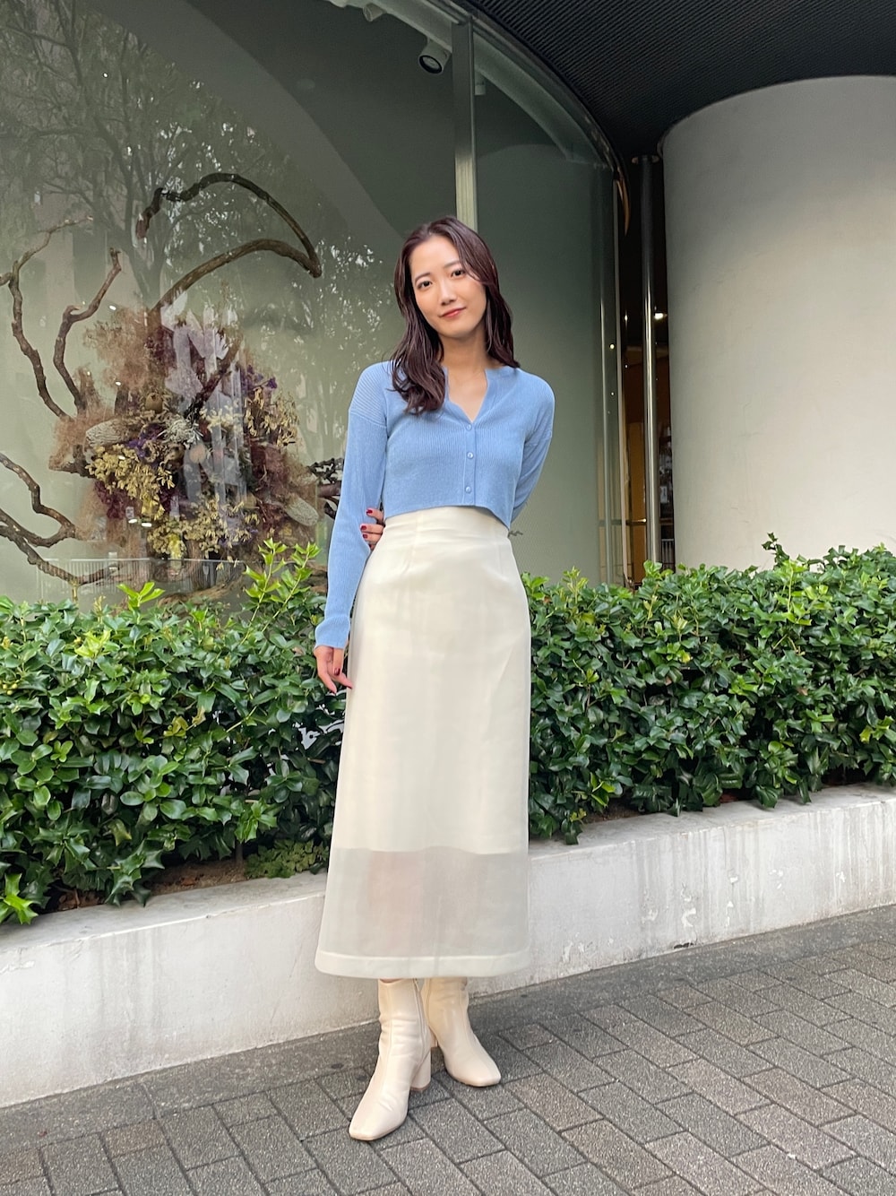 ホワイト系のブーツ、ホワイト系のスカート、ブルー系のカーディガン/ボレロを着用したレディースの秋コーディネートの1枚目の写真