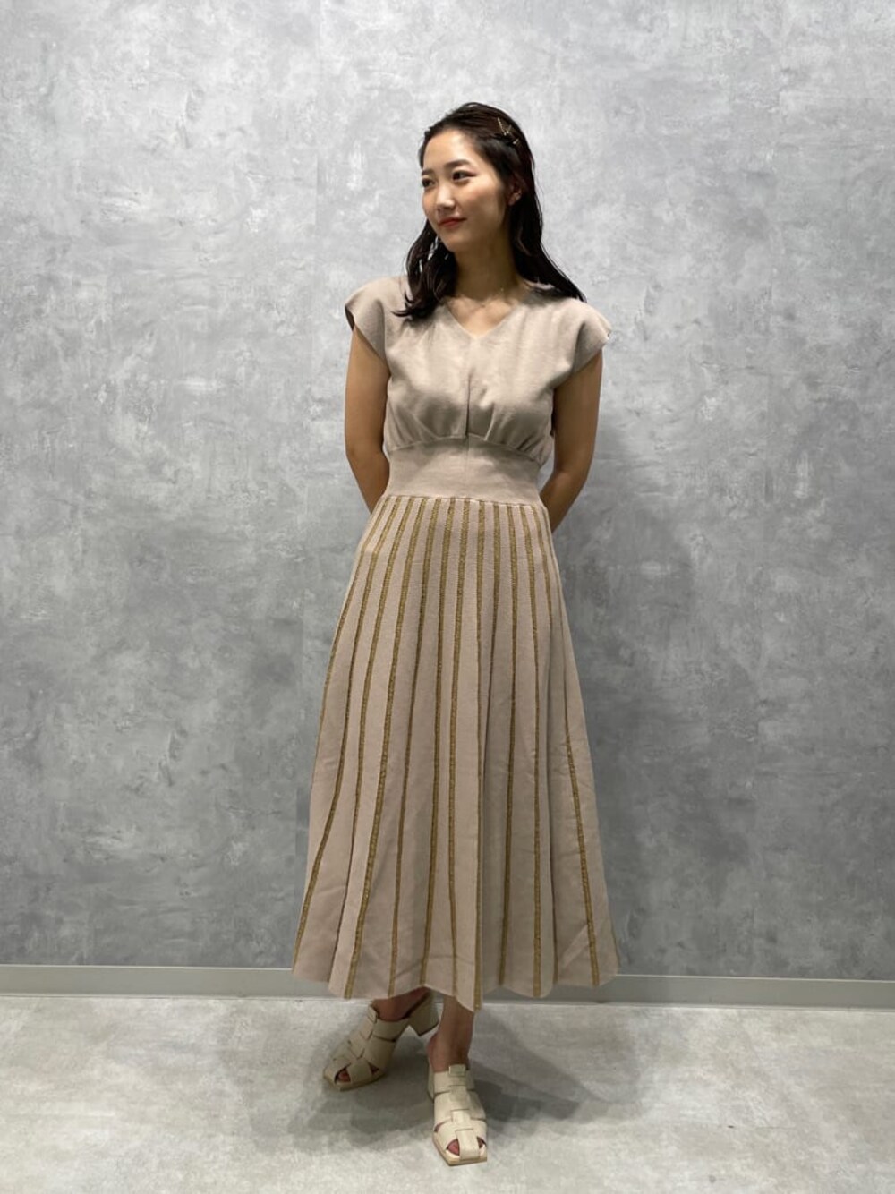 ホワイト系のサンダル、ベージュ系のワンピースを着用したレディースの夏コーディネートの1枚目の写真