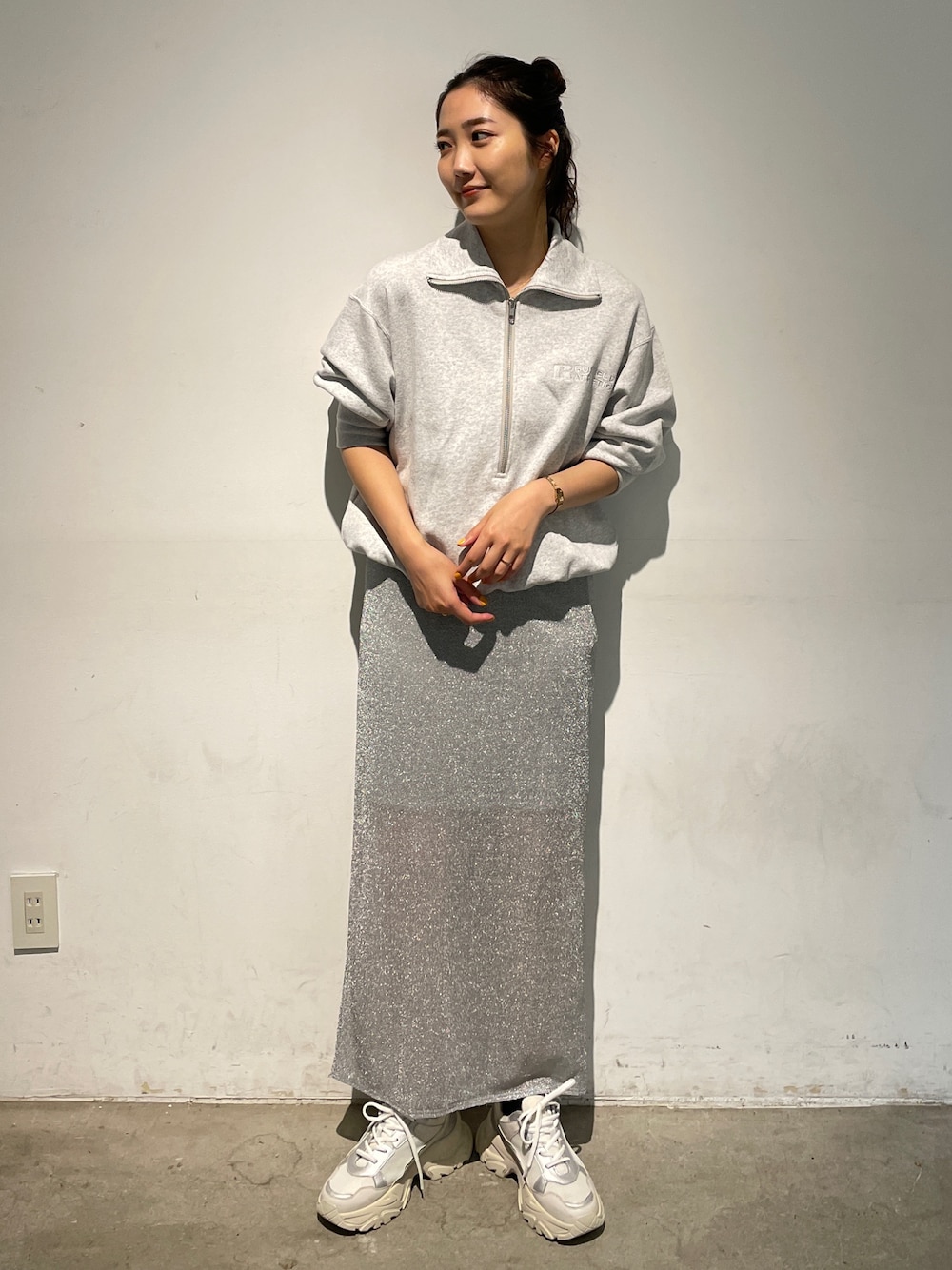 シルバー系のスカート、グレー系のスウェット、ホワイト系のスニーカーを着用したレディースの秋コーディネートの1枚目の写真