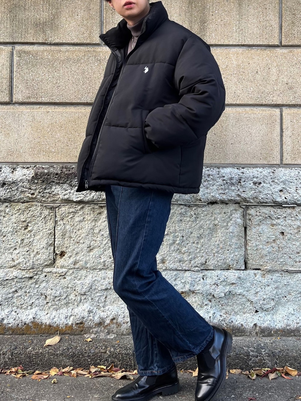 ブラック系のダウンジャケット/コート、グレー系のニット/セーター、ブルー系のデニムパンツを着用したメンズの冬コーディネートの1枚目の写真