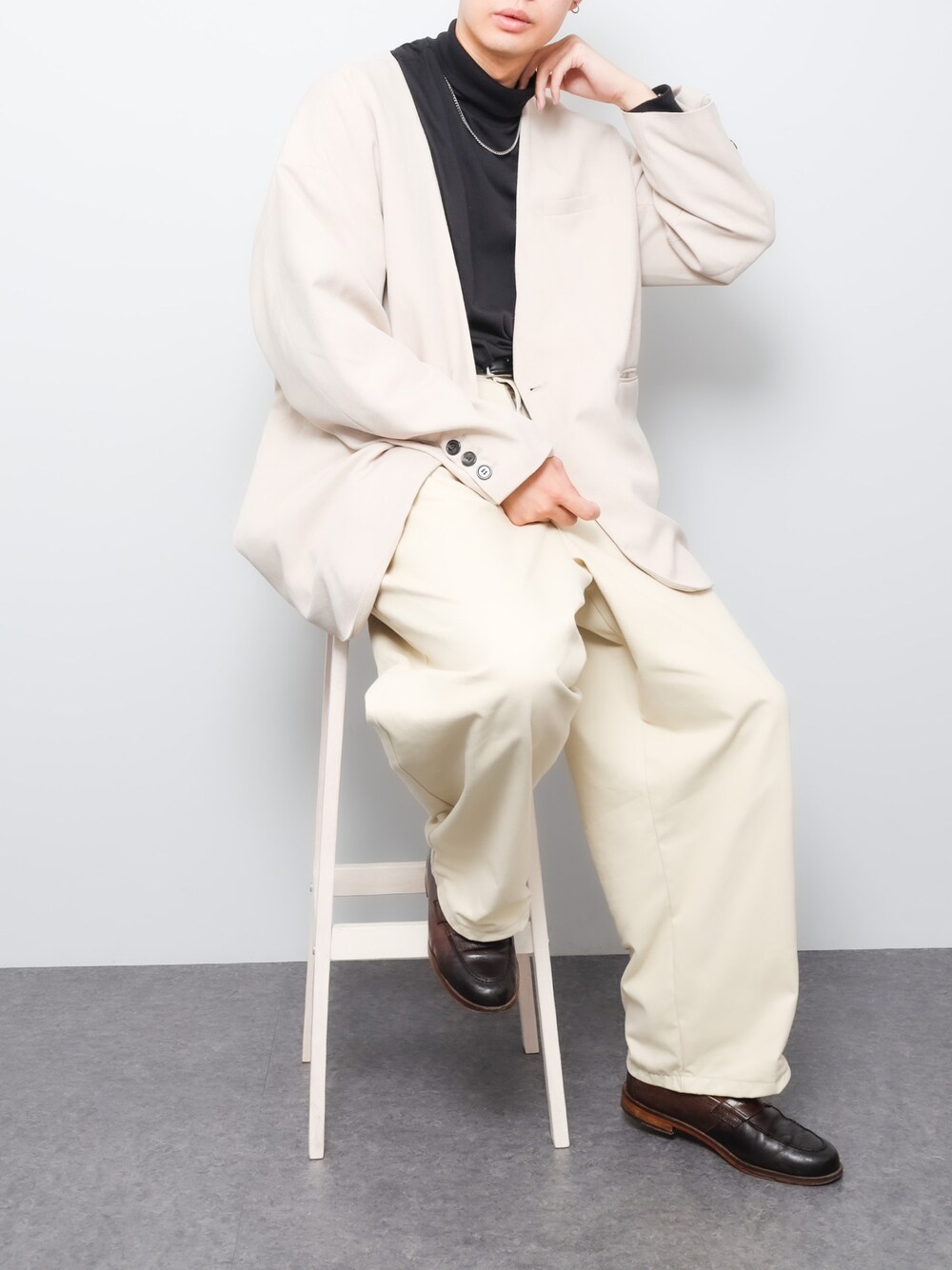 ベージュ系のノーカラージャケット、ブラック系のTシャツ/カットソー、ホワイト系のチノパンツを着用したメンズの秋コーディネートの1枚目の写真