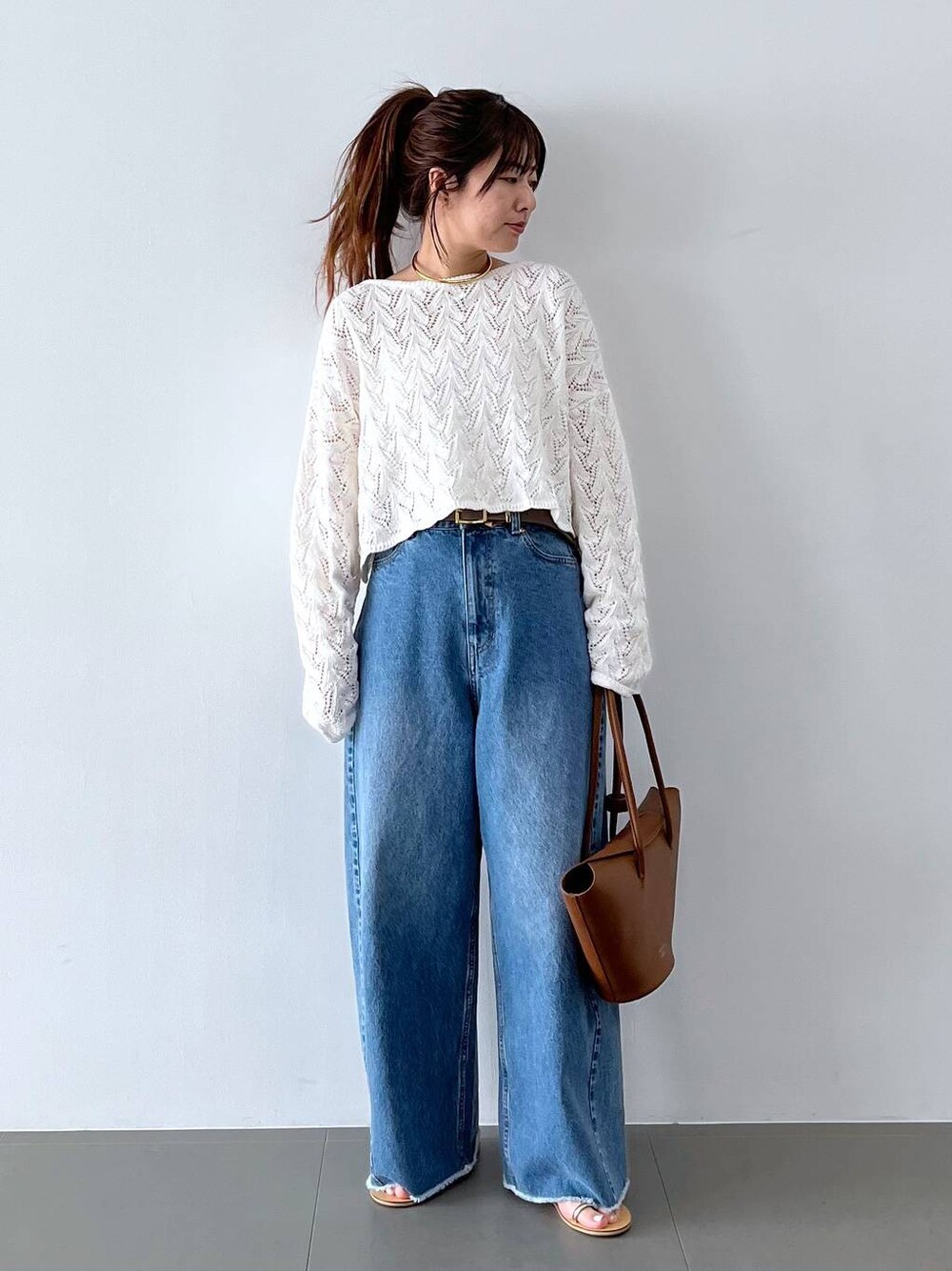 ブルー系のデニムパンツ、イエロー系のハンドバッグ、グレー系のベルトを着用したレディースの春コーディネートの1枚目の写真