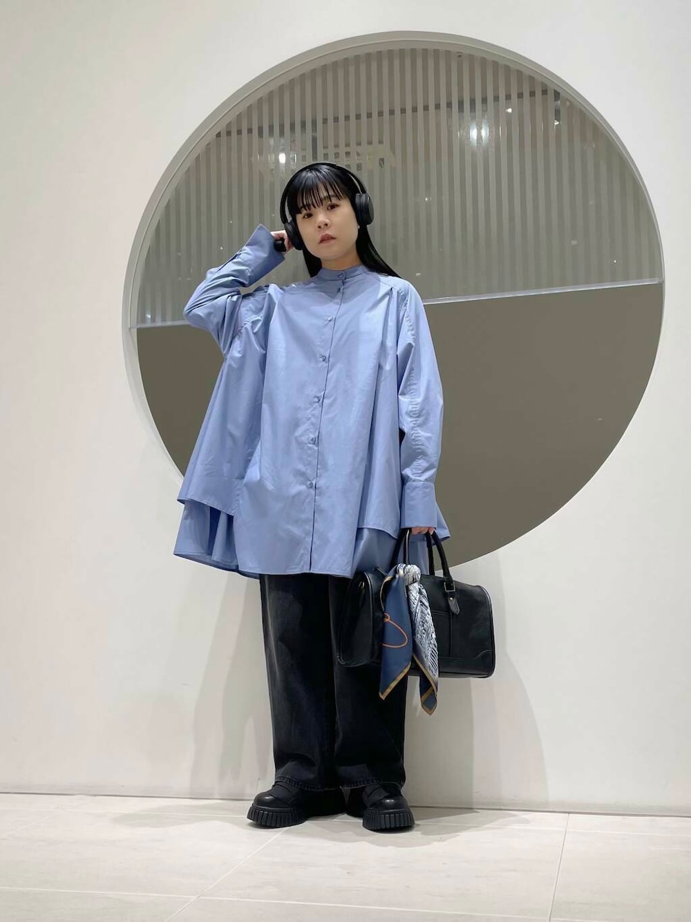 ブラック系のデニムパンツ、ブルー系のワンピース、ブラック系のスニーカーを着用したレディースの冬コーディネートの1枚目の写真