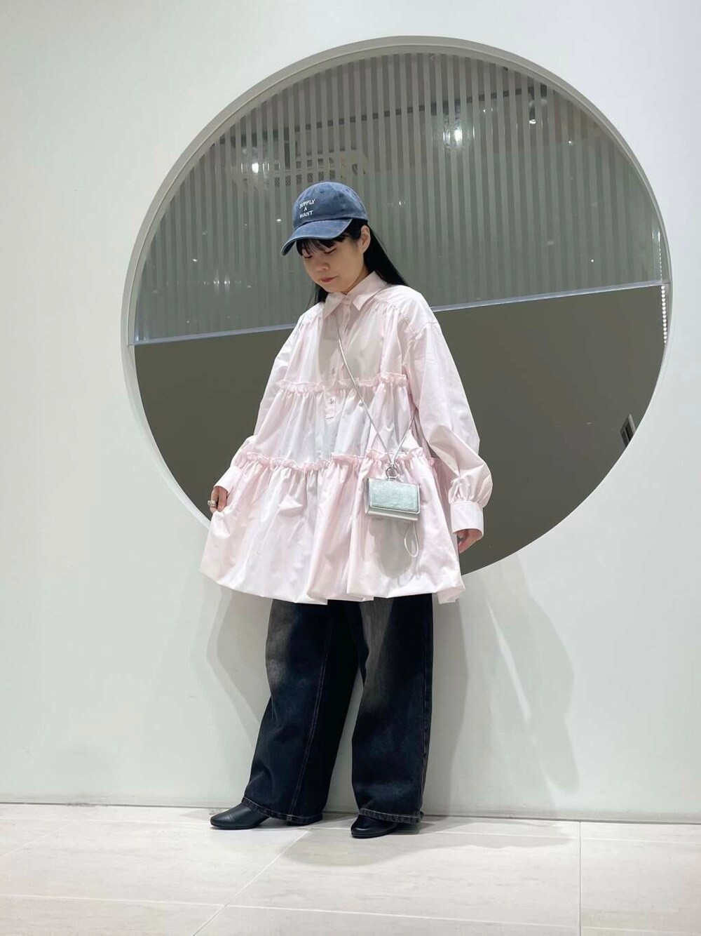 ブラック系のブーツ、ブラック系のデニムパンツ、ピンク系のワンピースを着用したレディースの冬コーディネートの1枚目の写真