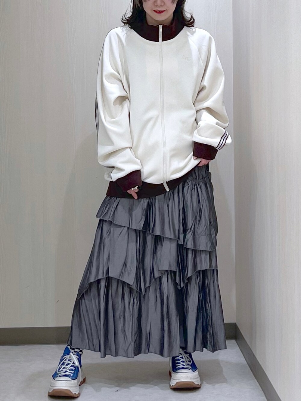 ホワイト系のブルゾン、グレー系のスカート、ブルー系のスニーカーを着用したレディースの春コーディネートの1枚目の写真