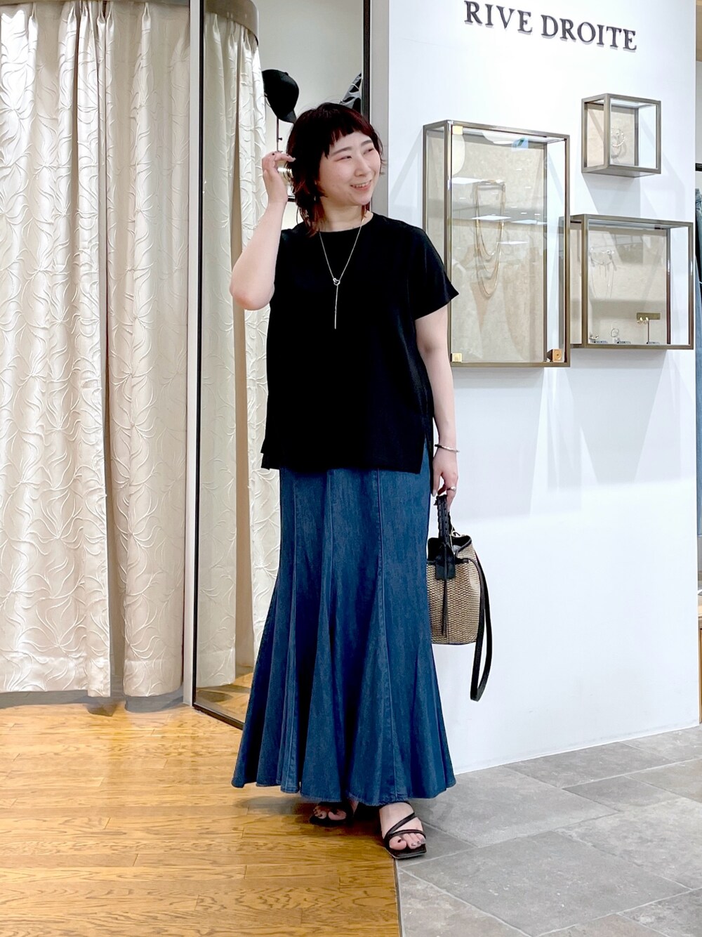 ブラック系のシャツ/ブラウス、ブルー系のスカート、ブラック系のハンドバッグを着用したレディースの春コーディネートの1枚目の写真