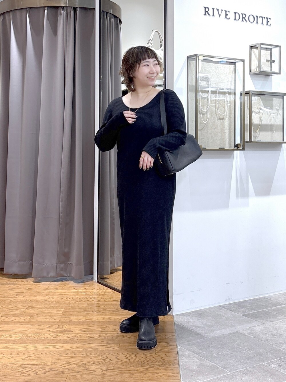 ブラック系のショルダーバッグ、ブラック系のワンピース、ブラック系のブーツを着用したレディースの秋コーディネートの1枚目の写真