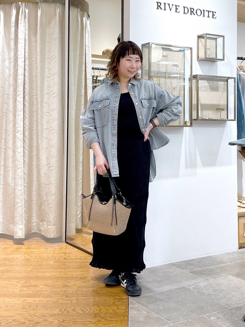 ブルー系のシャツ/ブラウス、ブラック系のニット/セーター、ブラック系のスカートを着用したレディースの春コーディネートの1枚目の写真