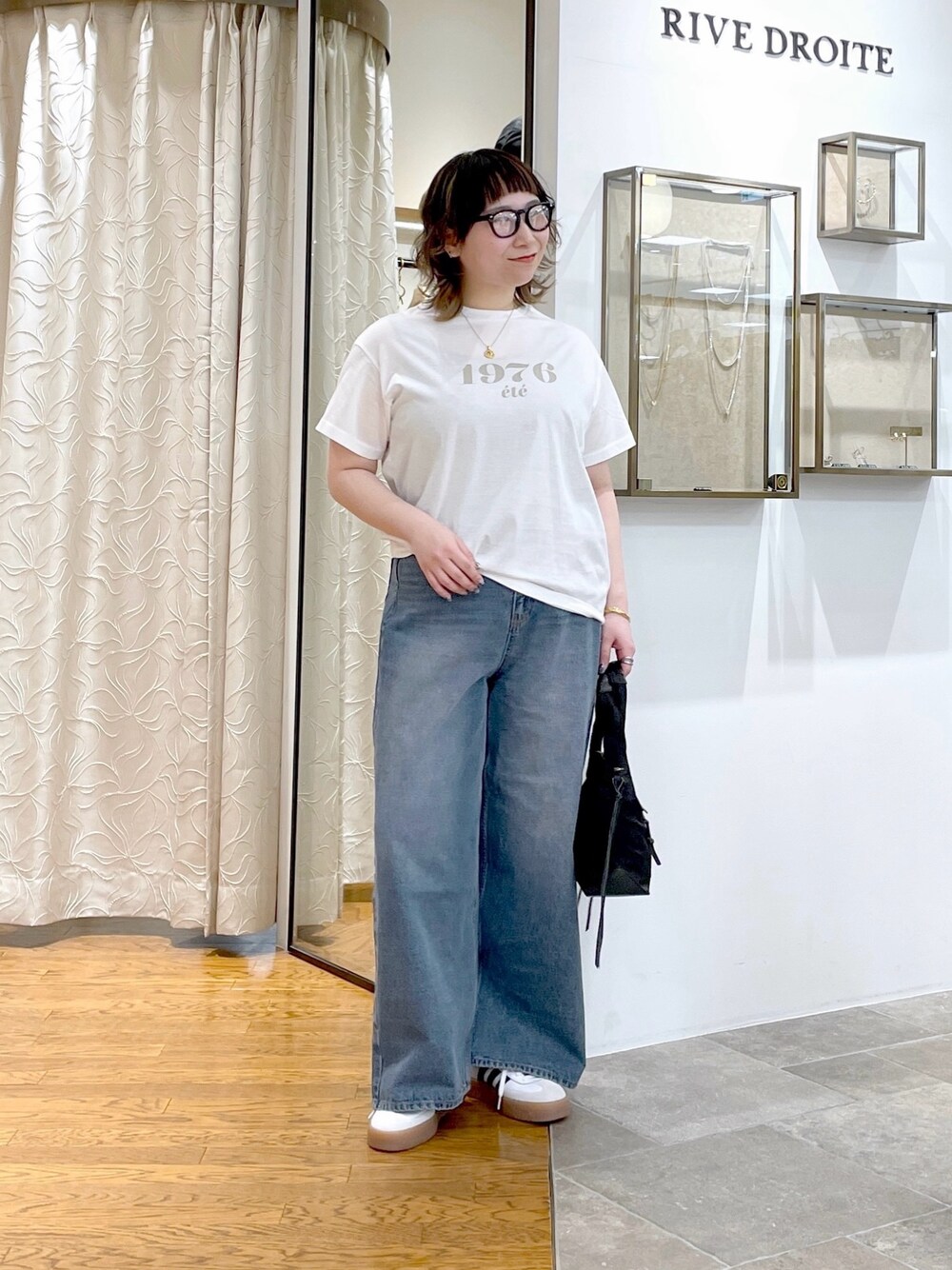 ホワイト系のTシャツ/カットソー、ブラック系のハンドバッグ、ブルー系のデニムパンツを着用したレディースの春コーディネートの1枚目の写真