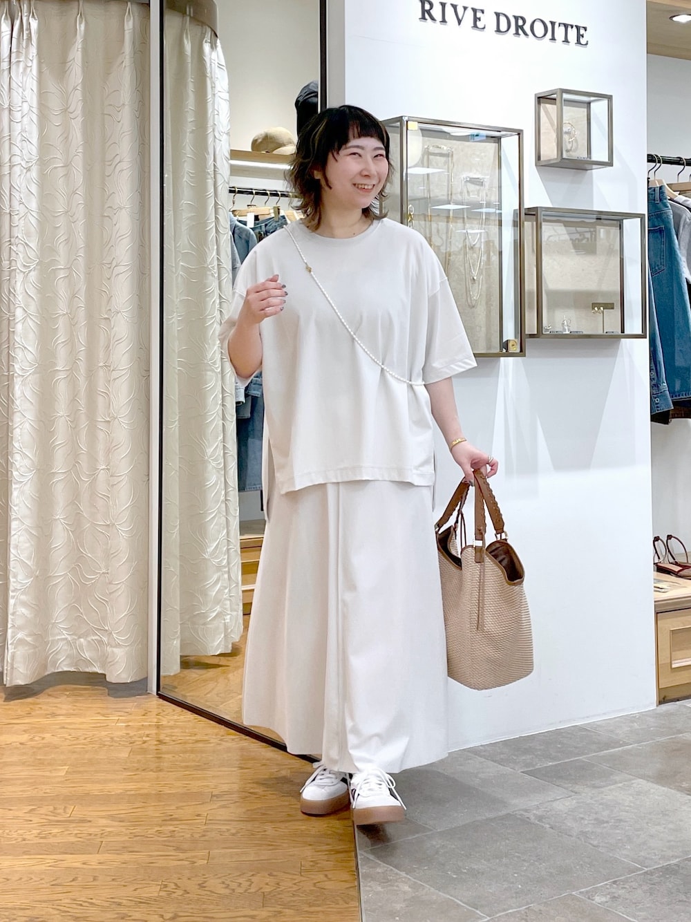 ホワイト系のTシャツ/カットソー、ブラウン系のトートバッグ、ホワイト系のスカートを着用したレディースの春コーディネートの1枚目の写真