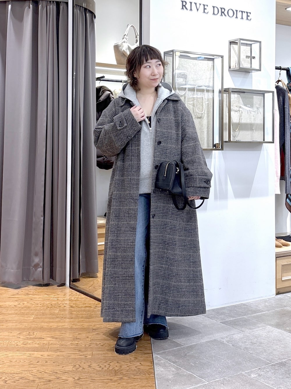 グレー系のパーカー、ブラック系のショルダーバッグ、グレー系のステンカラーコートを着用したレディースの秋コーディネートの1枚目の写真