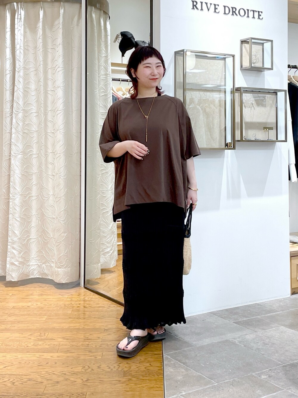 ブラウン系のTシャツ/カットソー、ブラック系のスカート、ゴールド系のネックレスを着用したレディースの春コーディネートの1枚目の写真