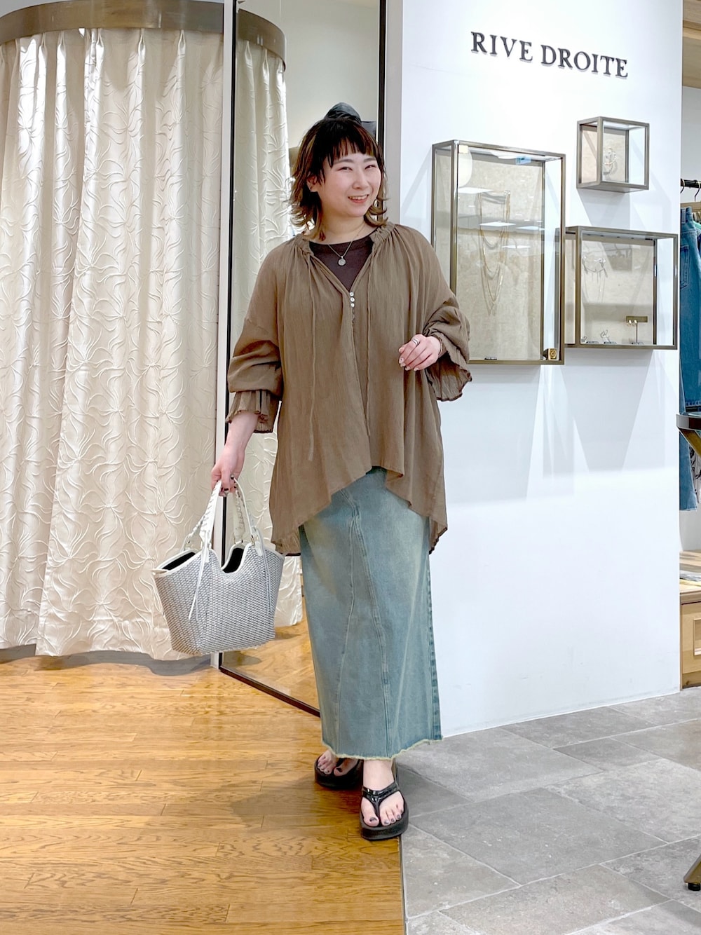 ブラウン系のキャミソール、ブラウン系のシャツ/ブラウス、ブルー系のデニムスカートを着用したレディースの春コーディネートの1枚目の写真