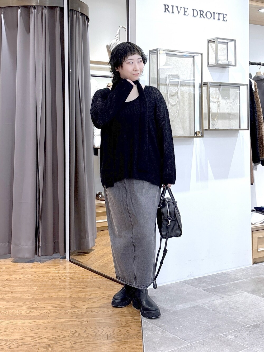 ブラック系のニット/セーター、グレー系のタンクトップ、ブラック系のボストンバッグを着用したレディースの秋コーディネートの1枚目の写真