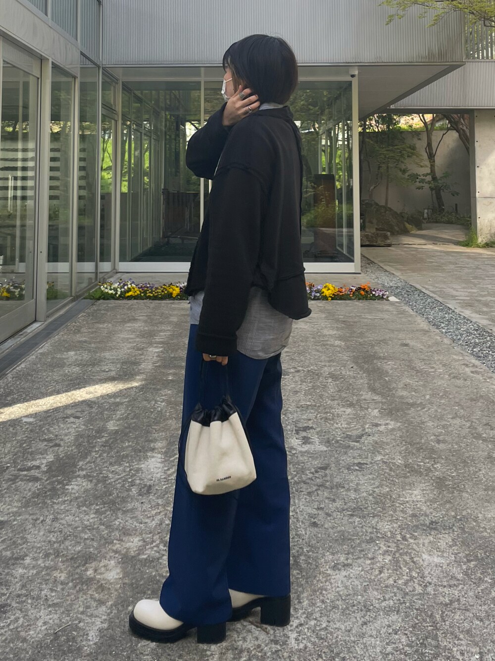 ブルー系のスラックス、ホワイト系のブーツ、ホワイト系のショルダーバッグを着用したレディースの春コーディネートの1枚目の写真